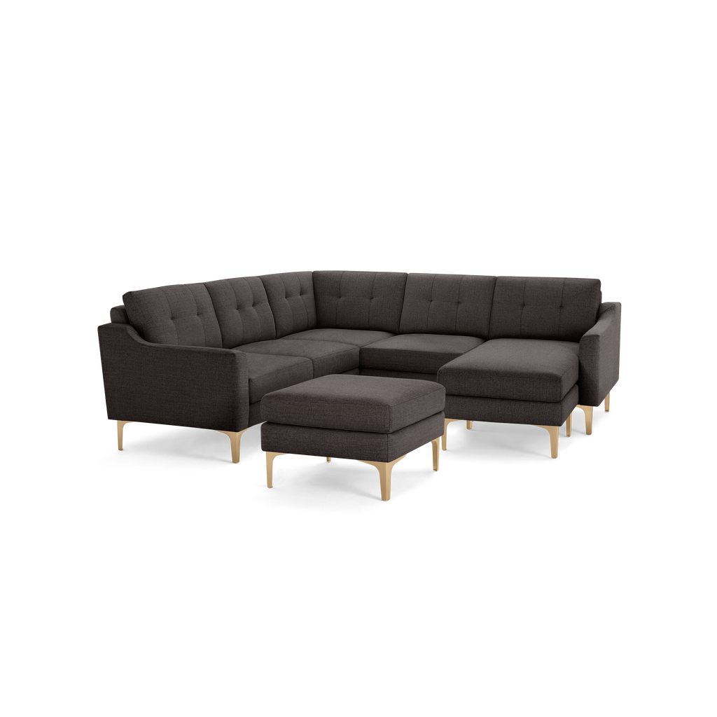 Dark gray fabric sectional sofa with tufted cushions, light wooden legs, and a matching ottoman.
