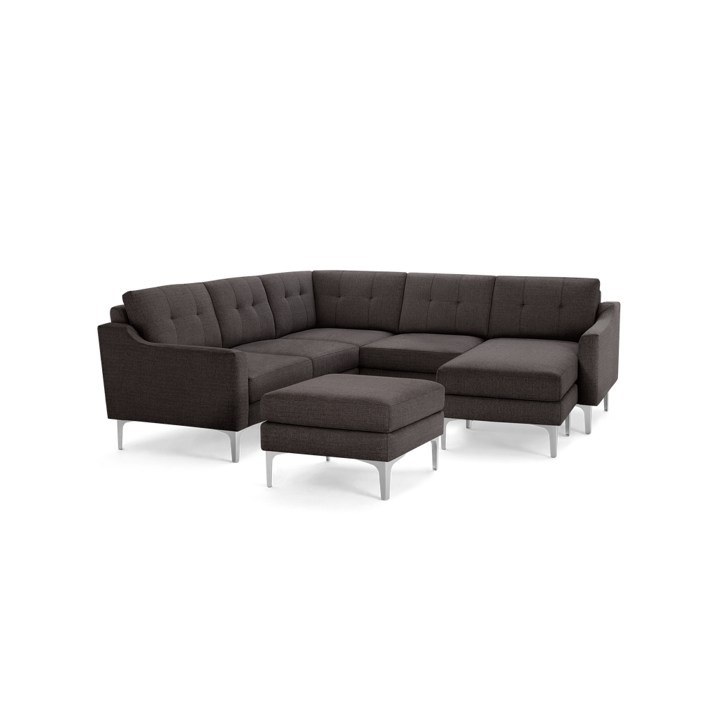 Dark gray modern sectional sofa with tufted cushions, metal legs, and a matching ottoman on black background.