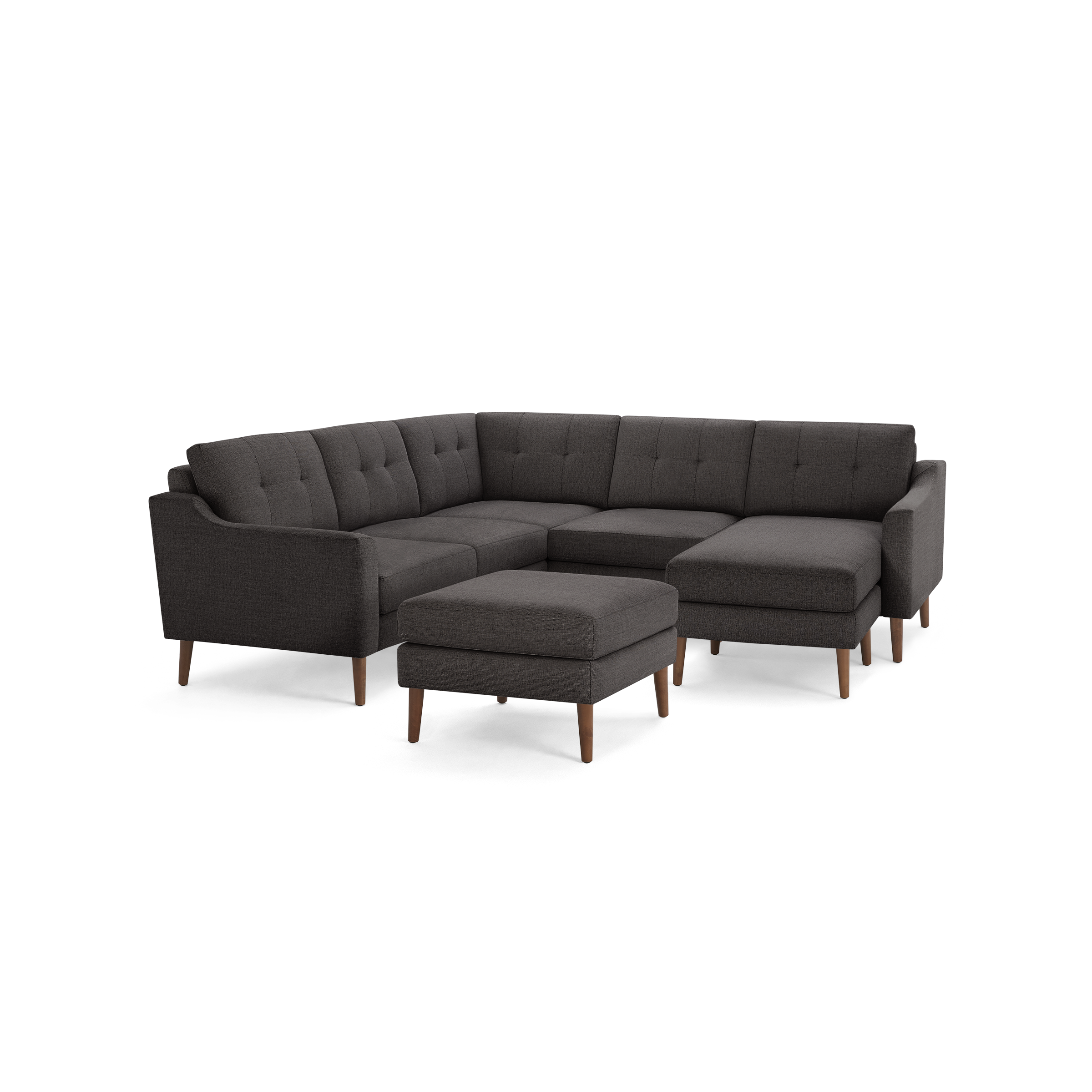 Dark gray upholstered sectional sofa with tufted back cushions, wooden tapered legs, and a matching ottoman.