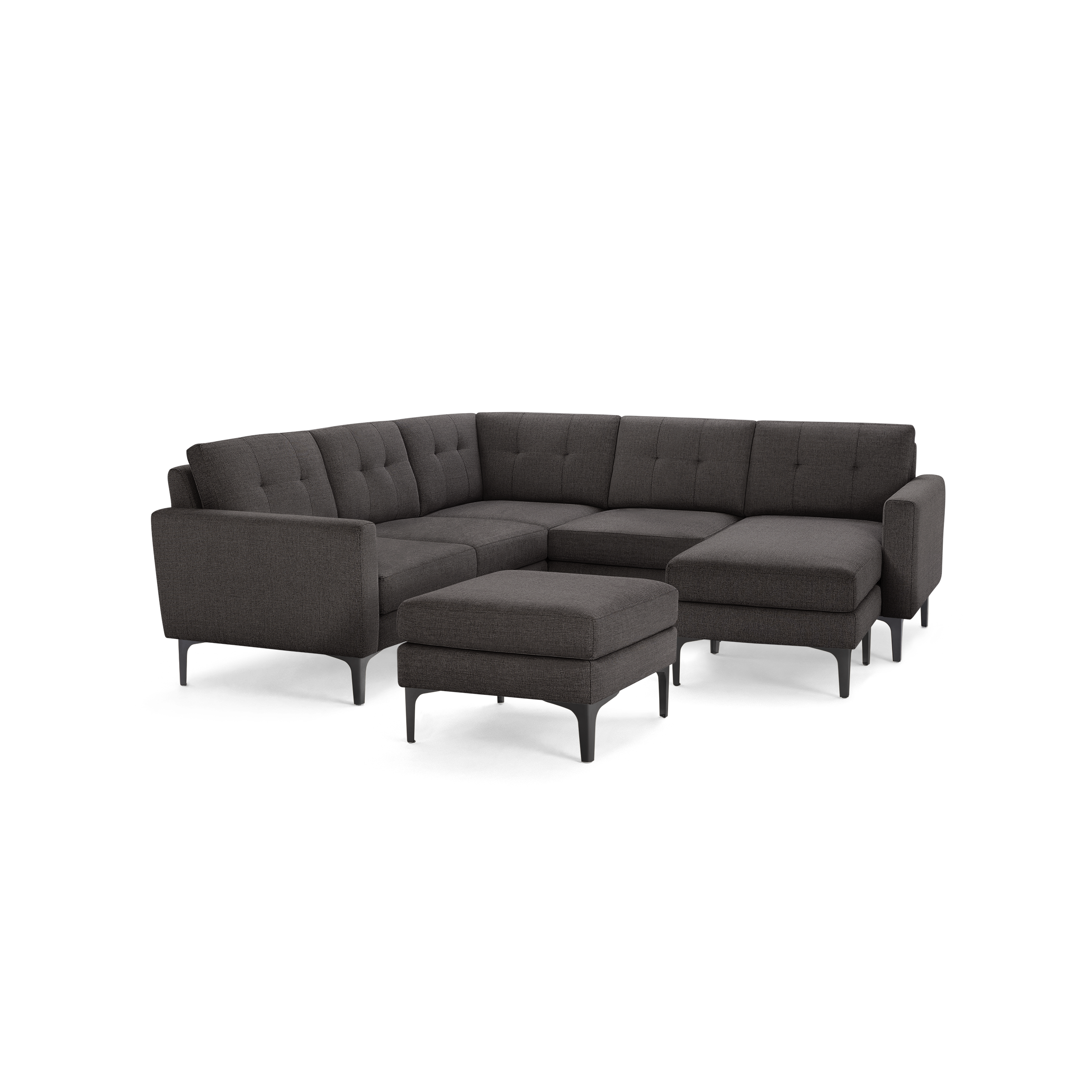 Dark gray upholstered fabric sectional sofa with tufted backrests, black slim metal legs, and a matching ottoman.