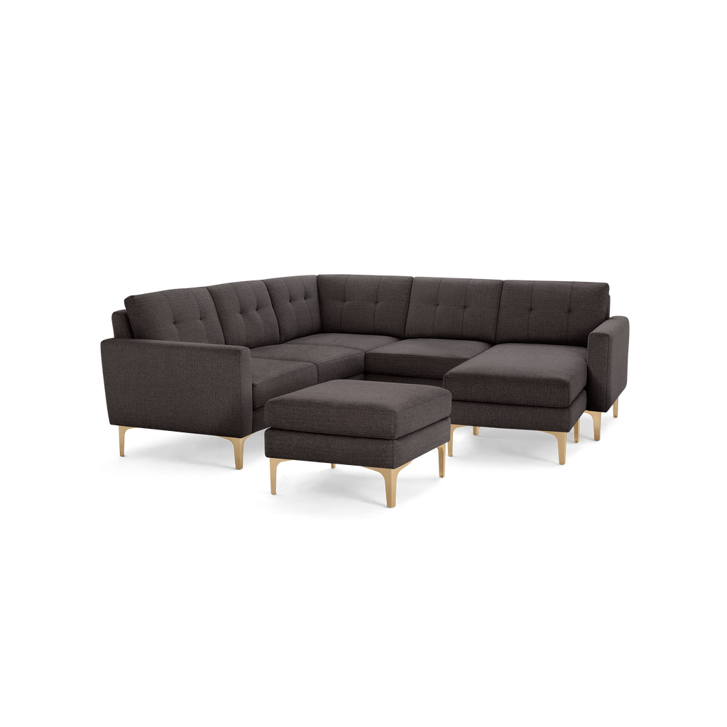 Dark gray modern L-shaped sectional sofa with tufted cushions and light wood legs, including a matching ottoman.