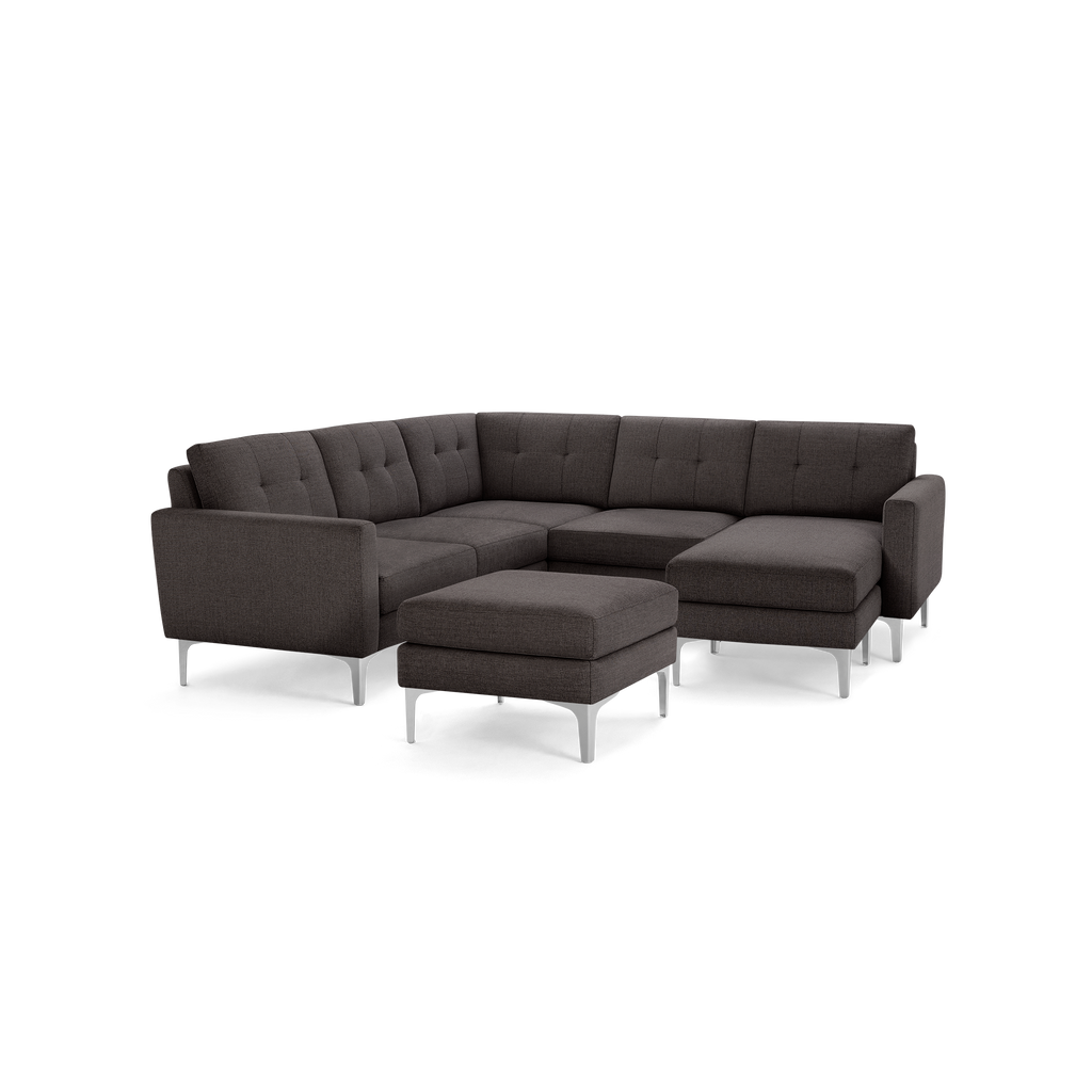 Dark gray modern sectional sofa with tufted cushions, metal legs, and a matching ottoman, shown on a black background.