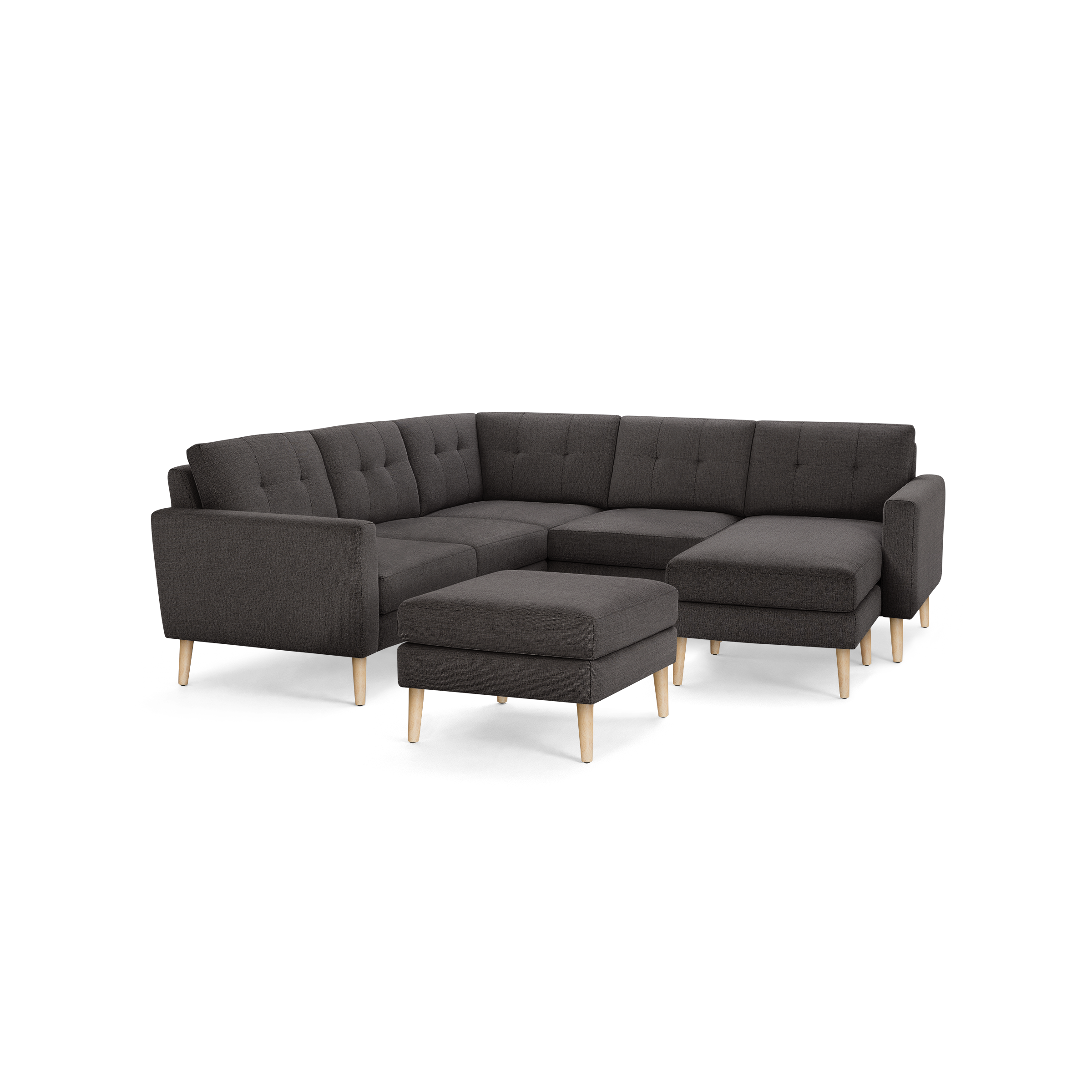 Dark gray fabric L-shaped sectional sofa with tufted cushions and light wooden legs, including a matching ottoman.