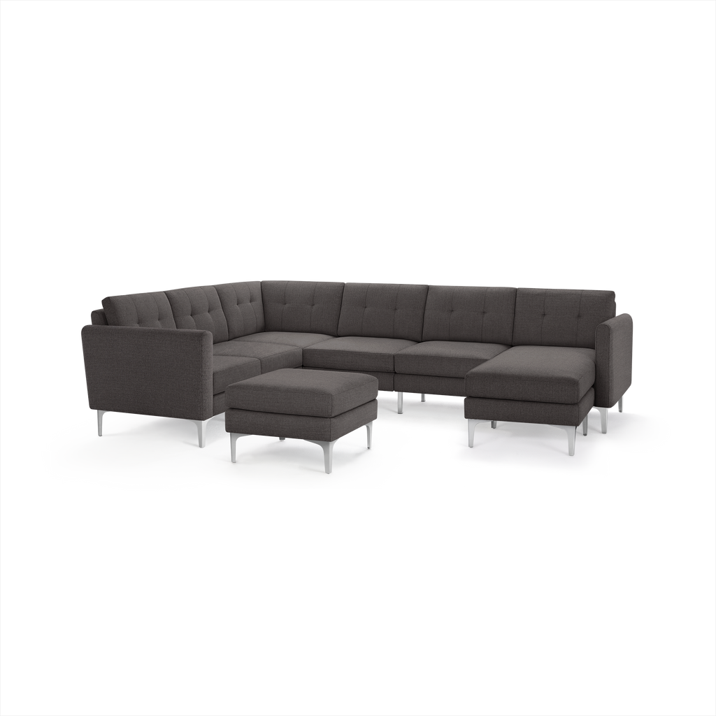 Dark gray modern sectional sofa with tufted back cushions, metal legs, and matching ottoman on white background.