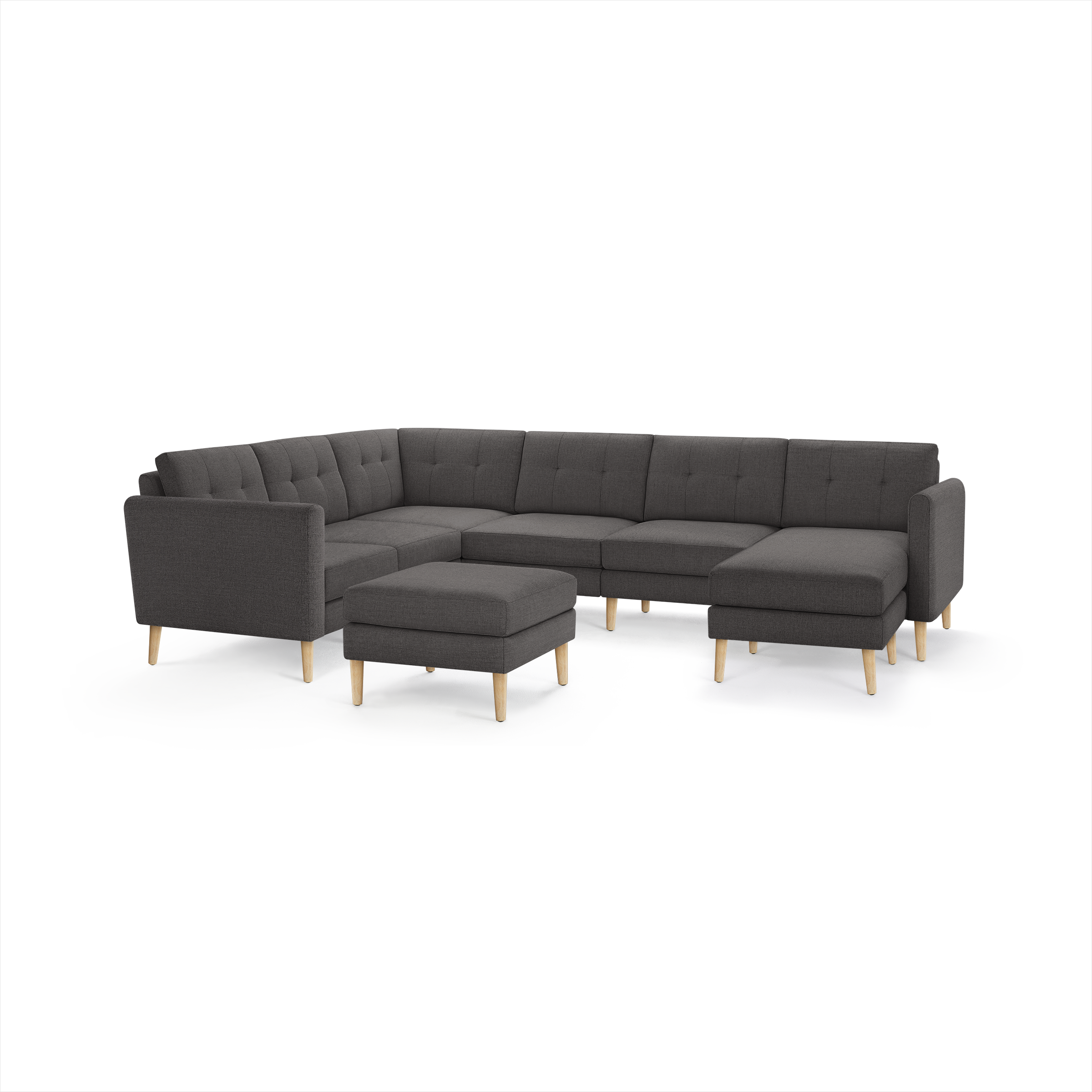 Dark gray fabric sectional sofa with tufted cushions, wooden legs, and matching ottoman, modern mid-century design.