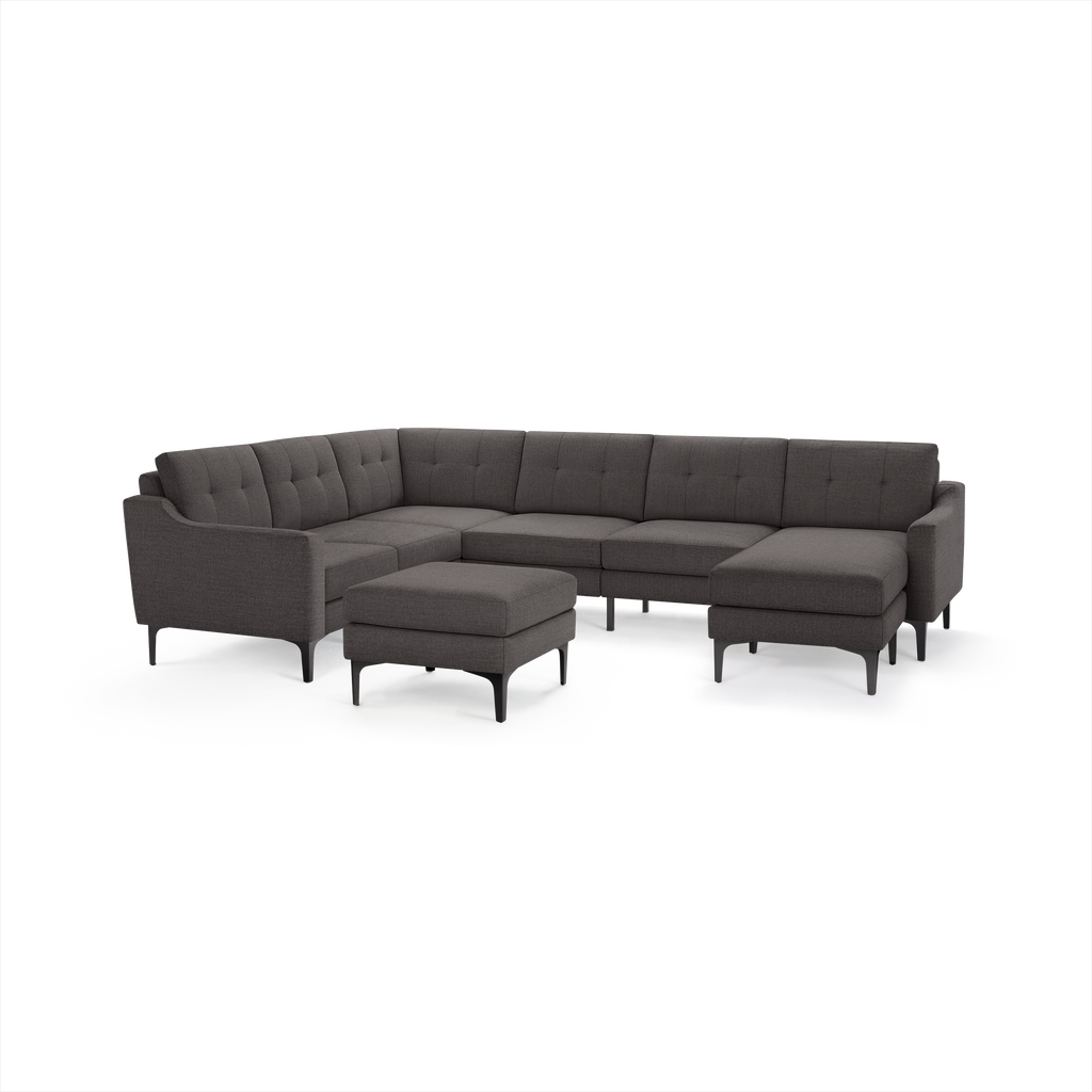 Dark gray L-shaped sectional sofa with tufted cushions, sleek armrests, metal legs, and a matching ottoman.