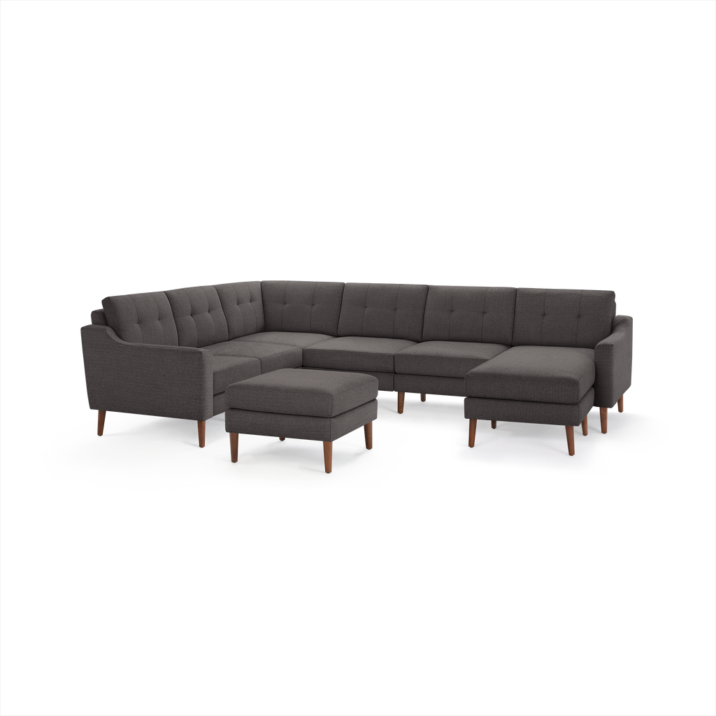 Large dark gray fabric sectional sofa with button-tufted cushions, wooden legs, and matching ottoman.