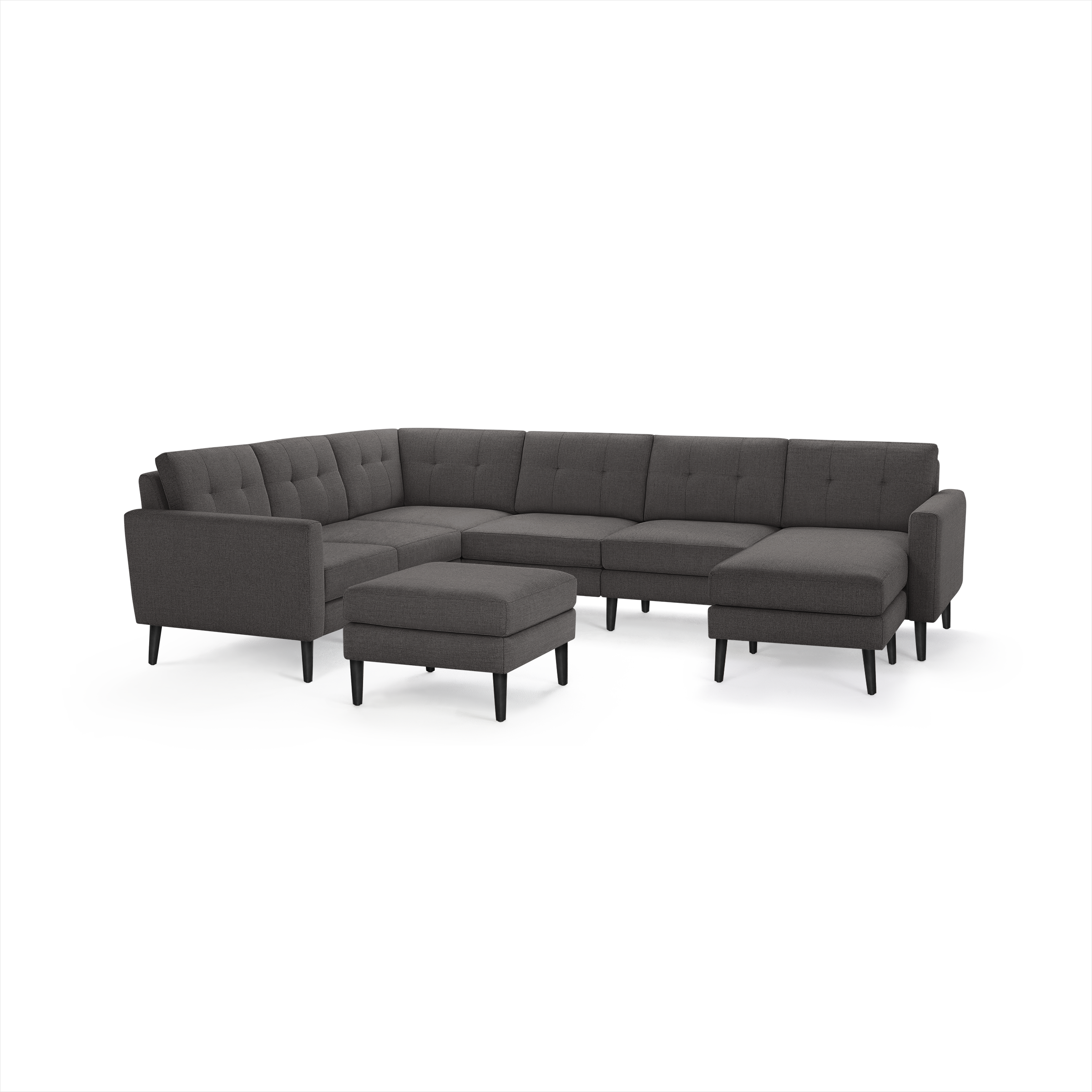 Dark gray fabric sectional sofa with tufted back cushions, sleek armrests, black tapered legs, and matching ottoman.