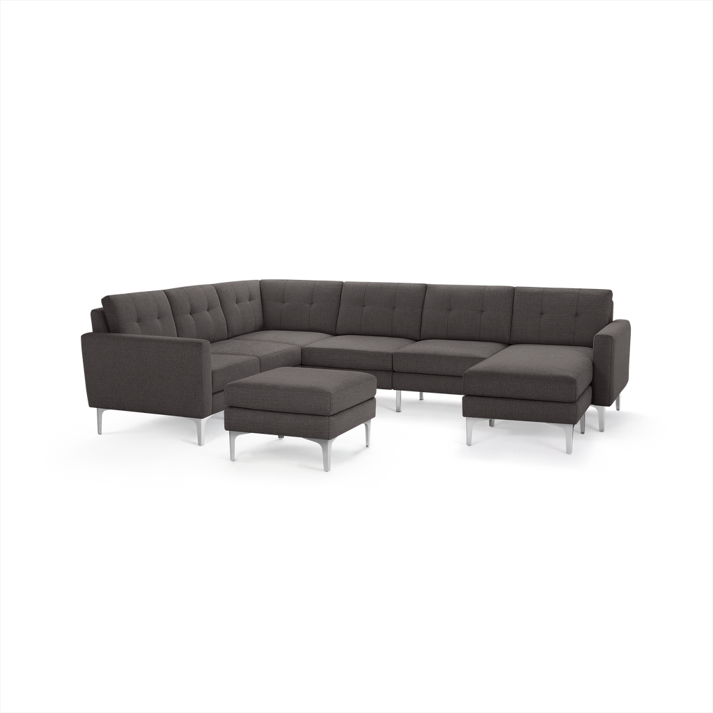 Dark gray modern sectional sofa with tufted cushions, metal legs, and matching ottoman on white background.
