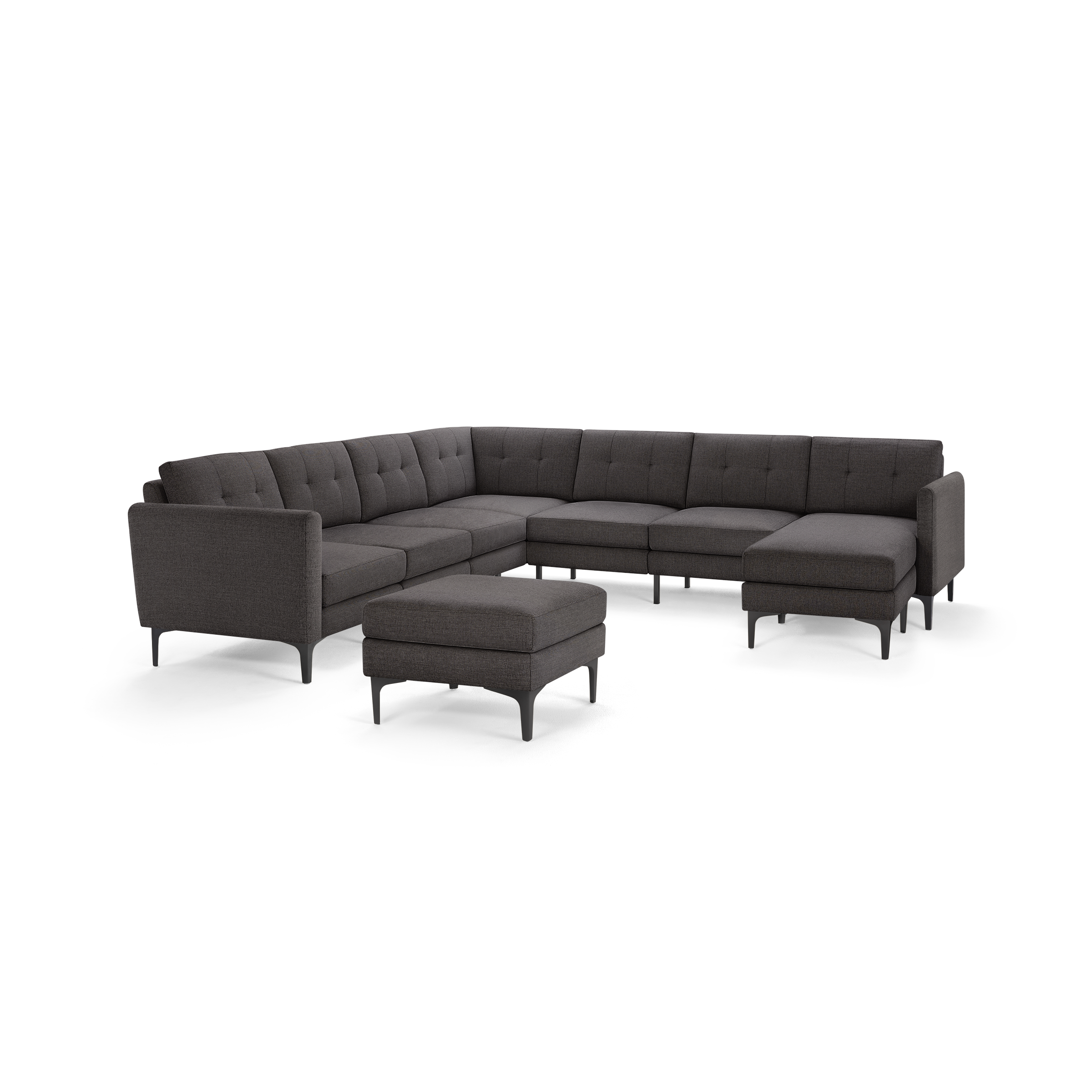 Modern L-shaped sectional sofa in dark gray fabric with tufted back cushions and matching ottoman, supported by sleek black legs.
