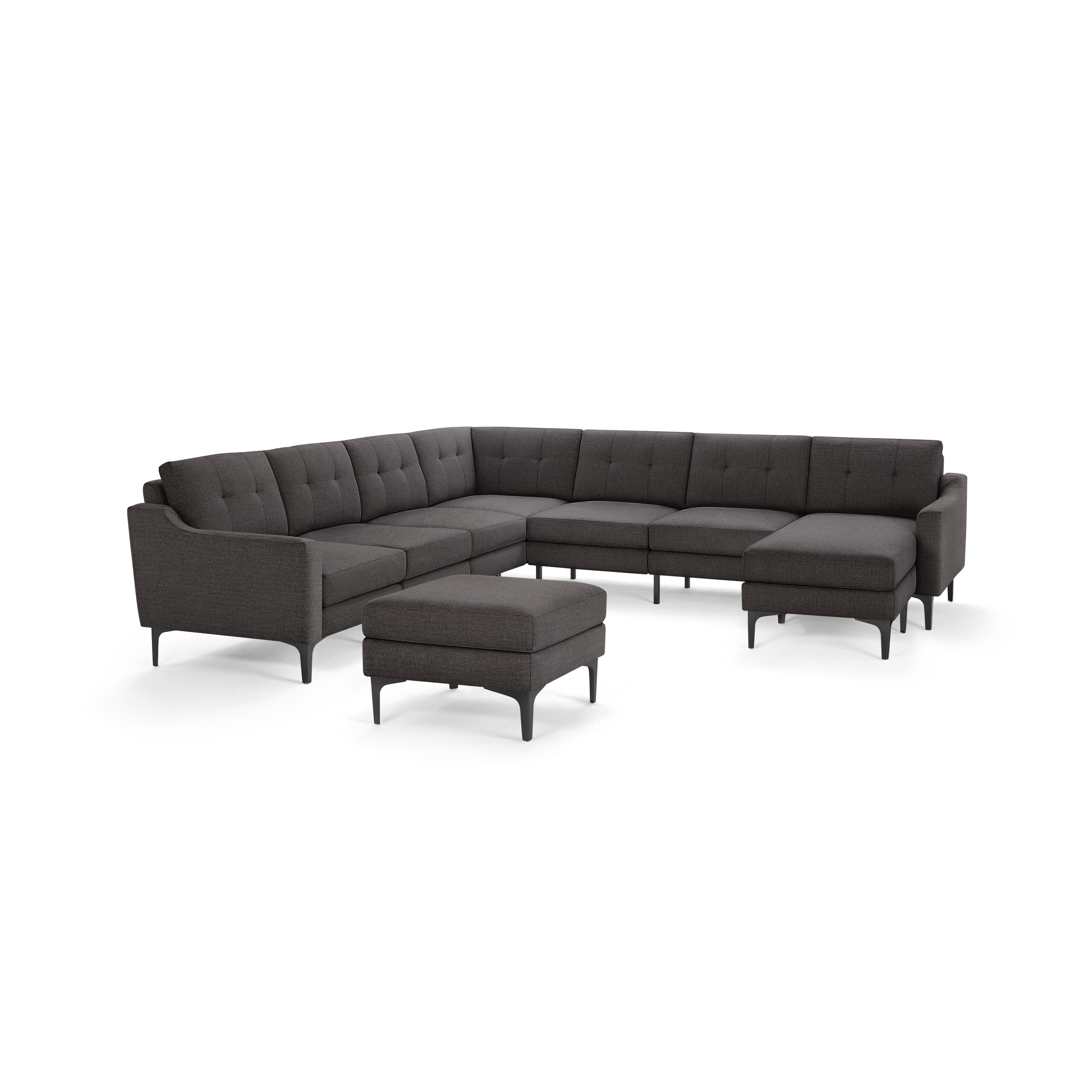 Dark gray upholstered modern sectional sofa with tufted back cushions and matching ottoman on black legs.