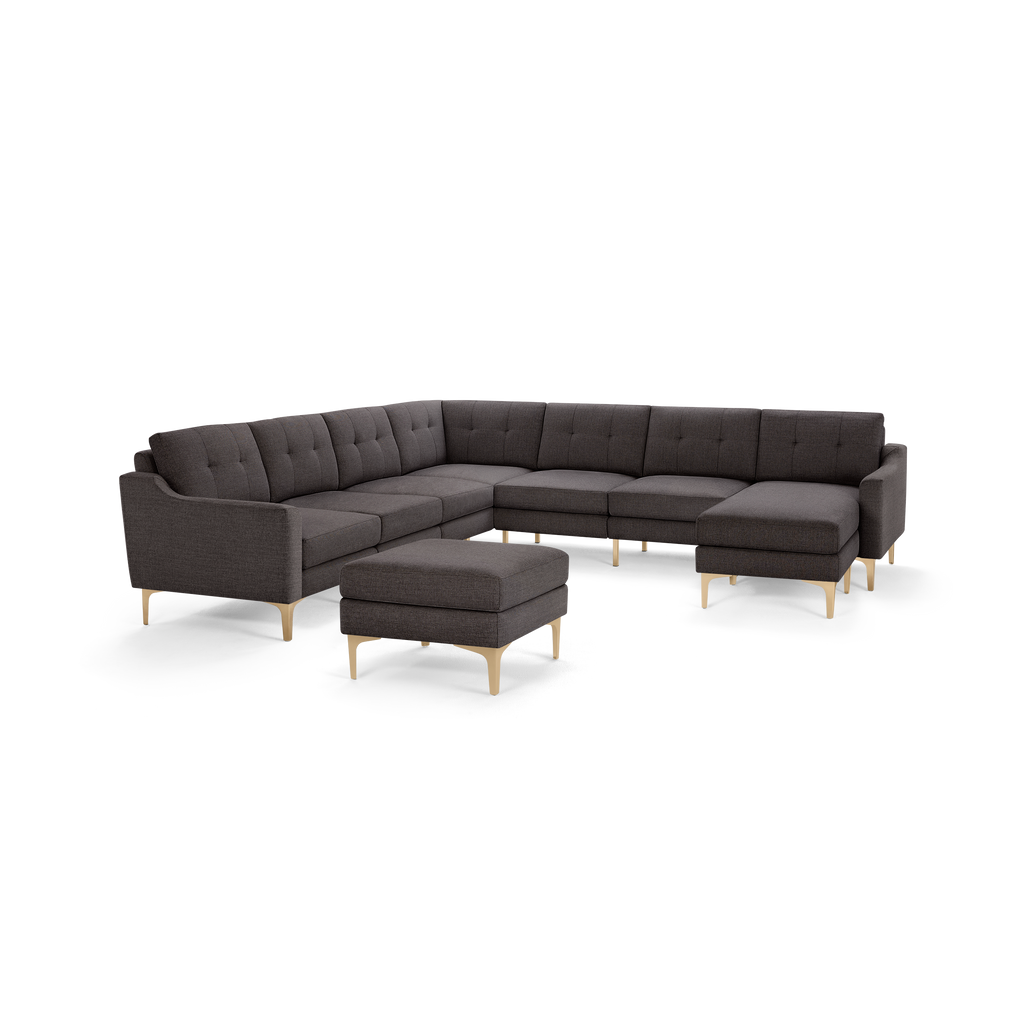 Dark gray L-shaped sectional sofa with tufted cushions, wooden angled legs, and a matching rectangular ottoman.