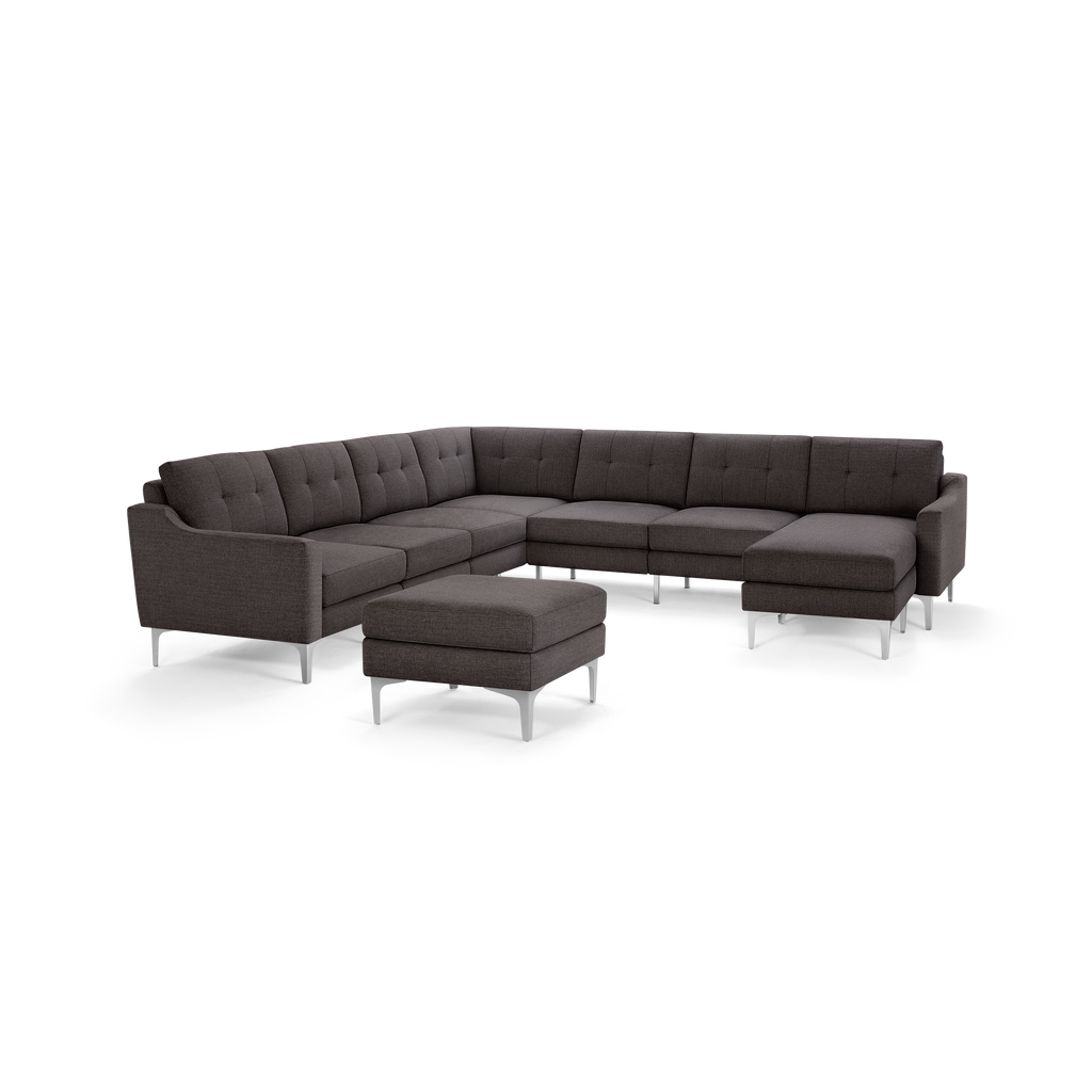 Dark gray L-shaped sectional sofa with tufted cushions and a matching ottoman on metal legs, modern design.
