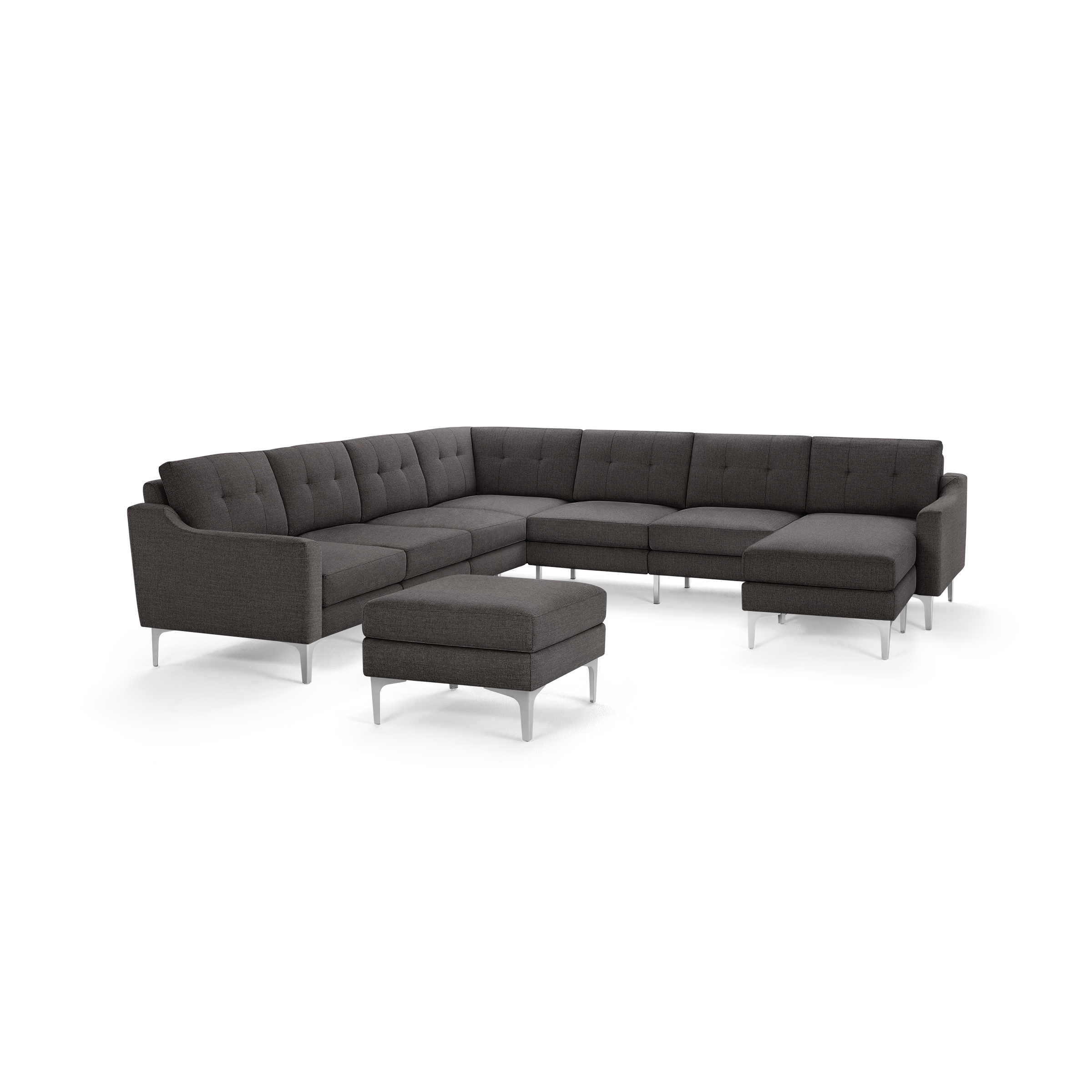 Dark gray L-shaped sectional sofa with tufted cushions and a matching ottoman on metal legs, modern design.