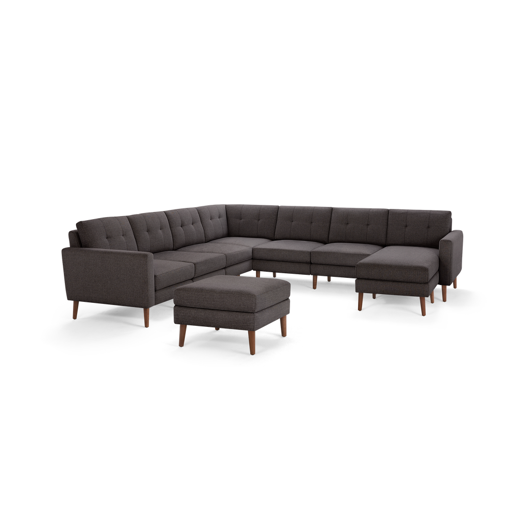 Modern dark gray fabric sectional sofa with tufted back cushions, wooden legs, and matching ottoman, designed for spacious living rooms.