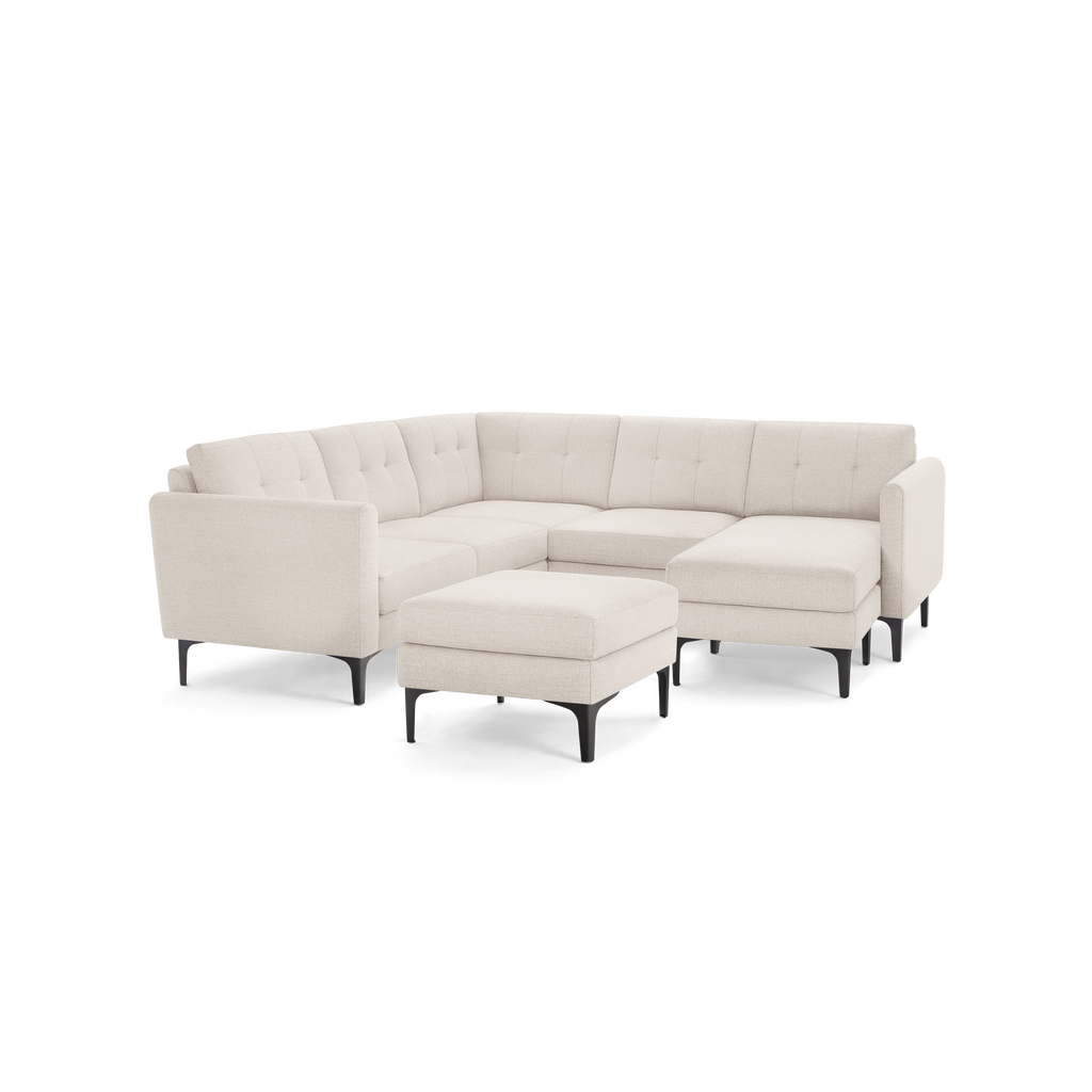 Light beige fabric sectional sofa with tufted back cushions, black metal legs, and a matching ottoman.