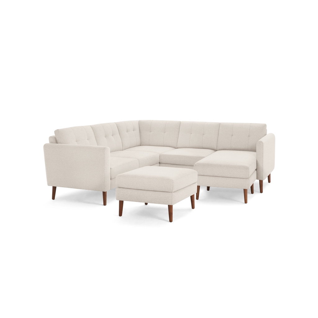 Light beige L-shaped sectional sofa with tufted cushions and wooden tapered legs, including a matching ottoman.