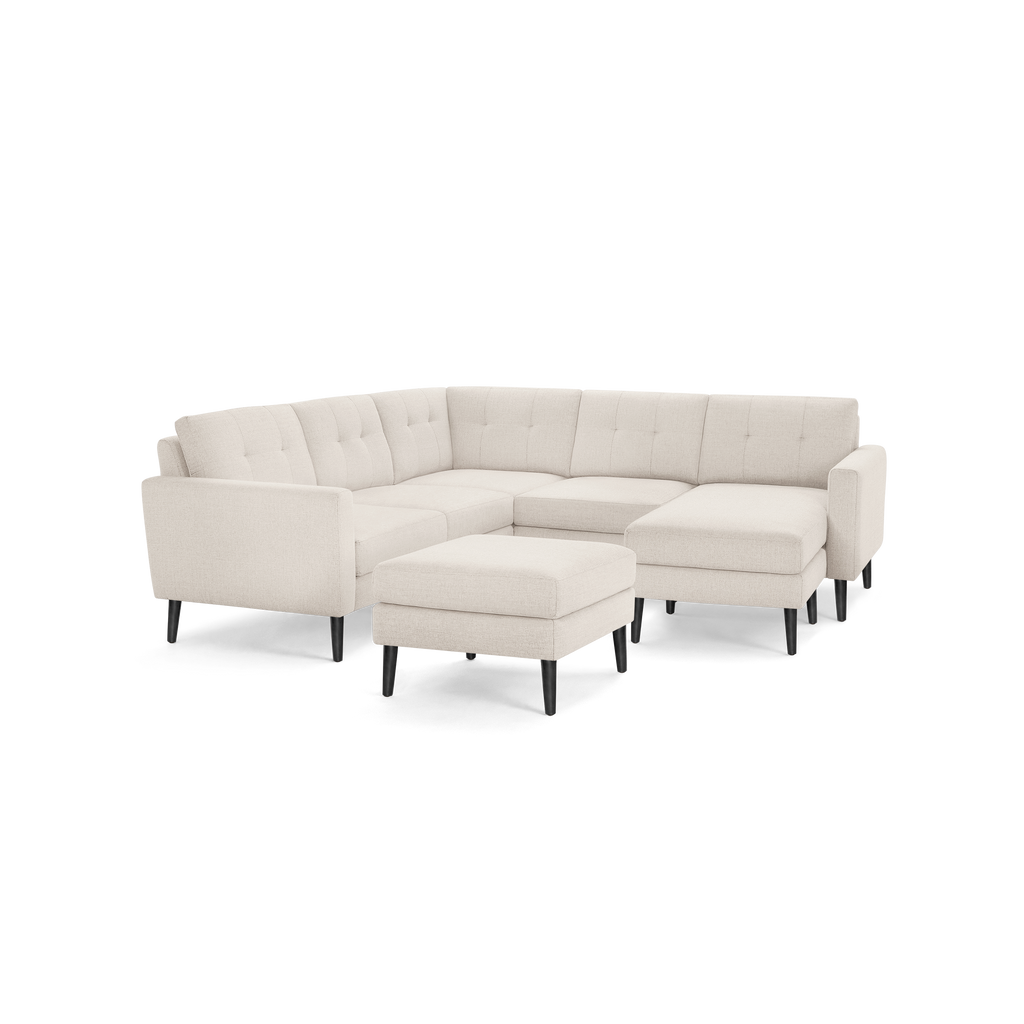 Modern beige fabric sectional sofa with tufted back cushions, right chaise, matching ottoman, and black tapered legs.