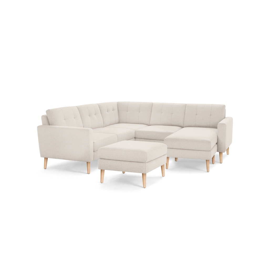 Beige upholstered modern sectional sofa with button-tufted cushions, wooden legs, and a matching ottoman.