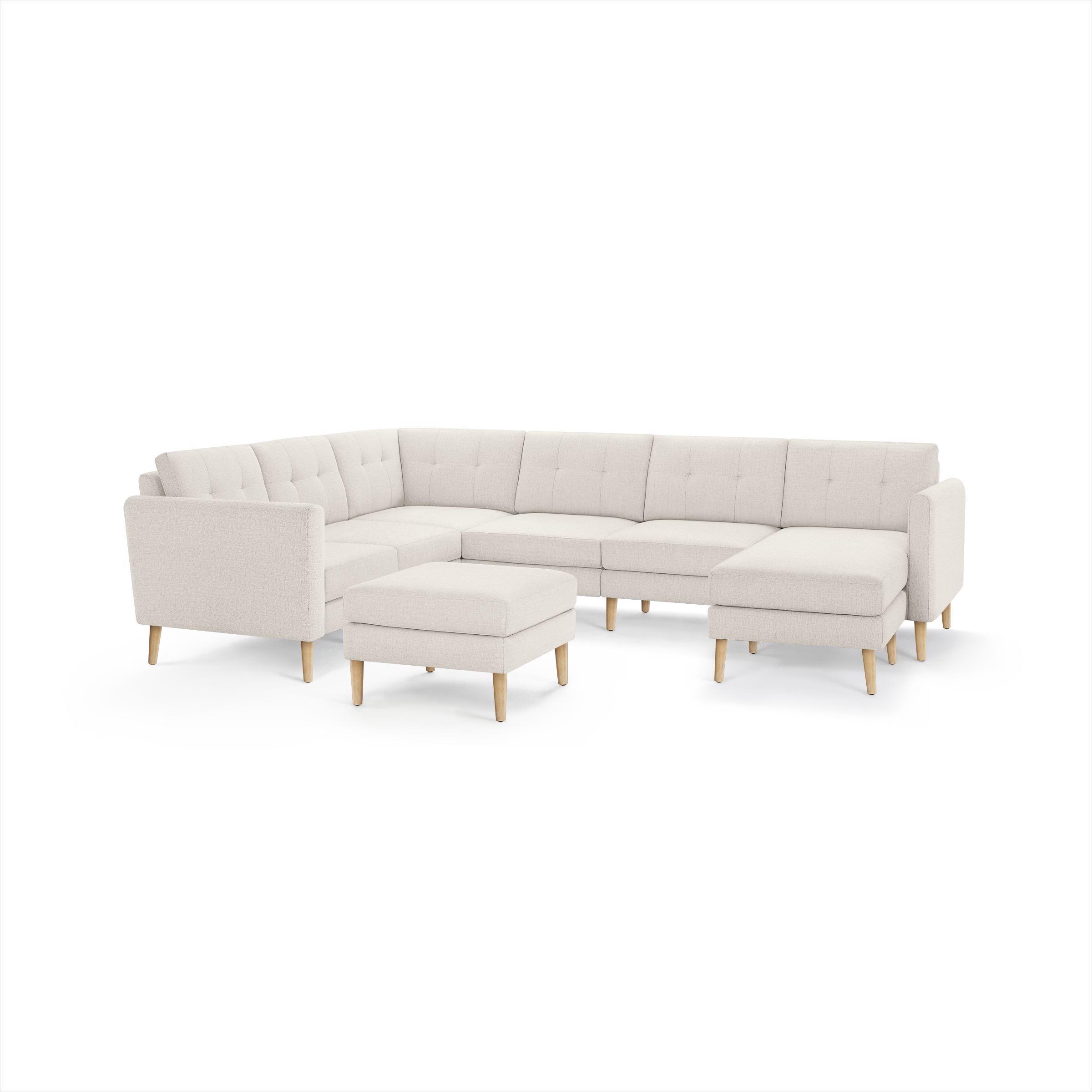 Cream-colored modern sectional sofa with tufted cushions, wooden legs, and matching ottoman, arranged in an L-shape.