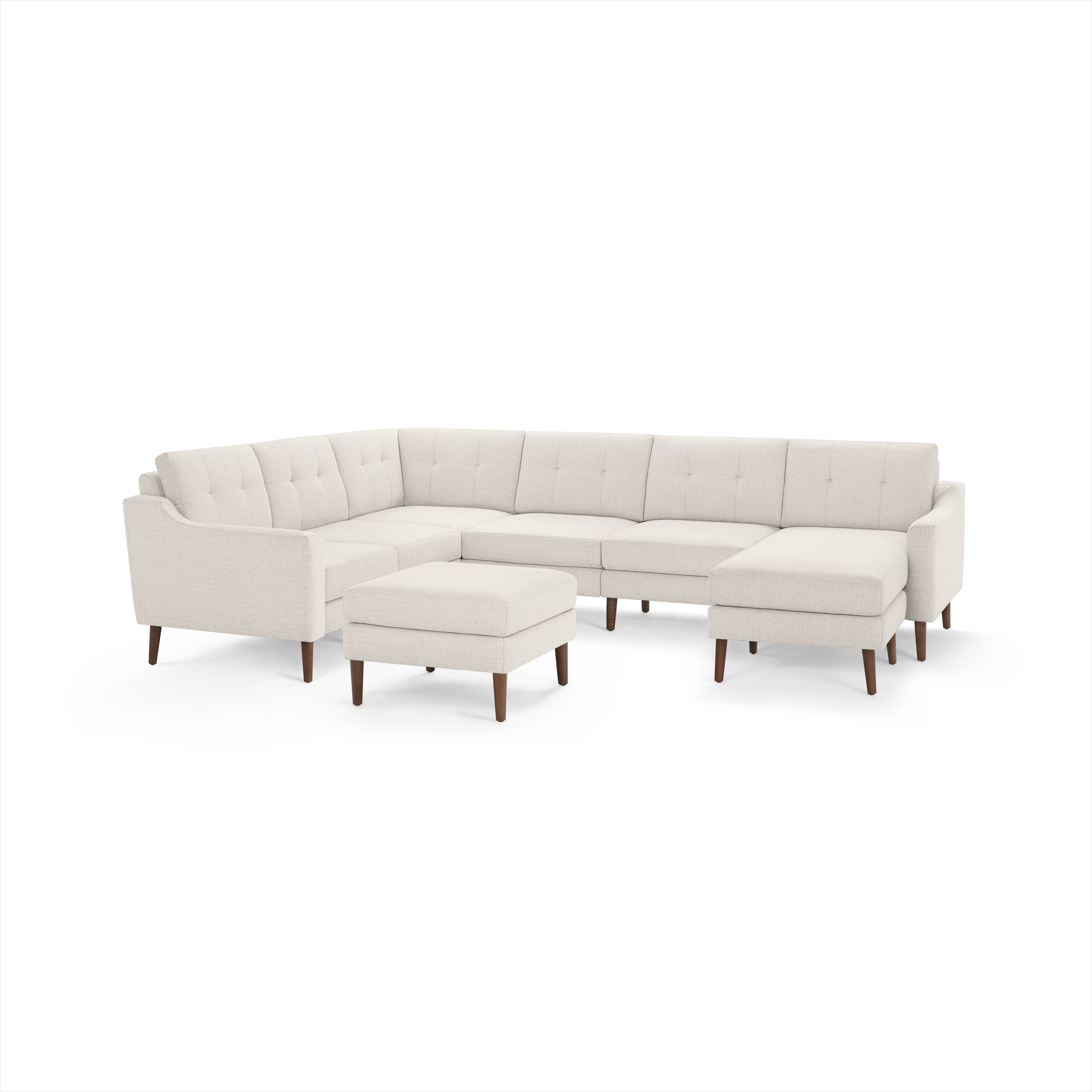 Beige fabric sectional sofa with tufted back cushions, wooden legs, and matching ottoman on a white background.