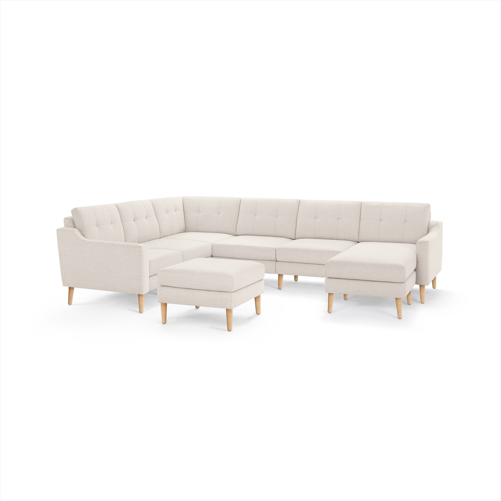 Cream-colored modern sectional sofa with tufted cushions, wooden legs, and a matching ottoman, arranged in an L-shape.