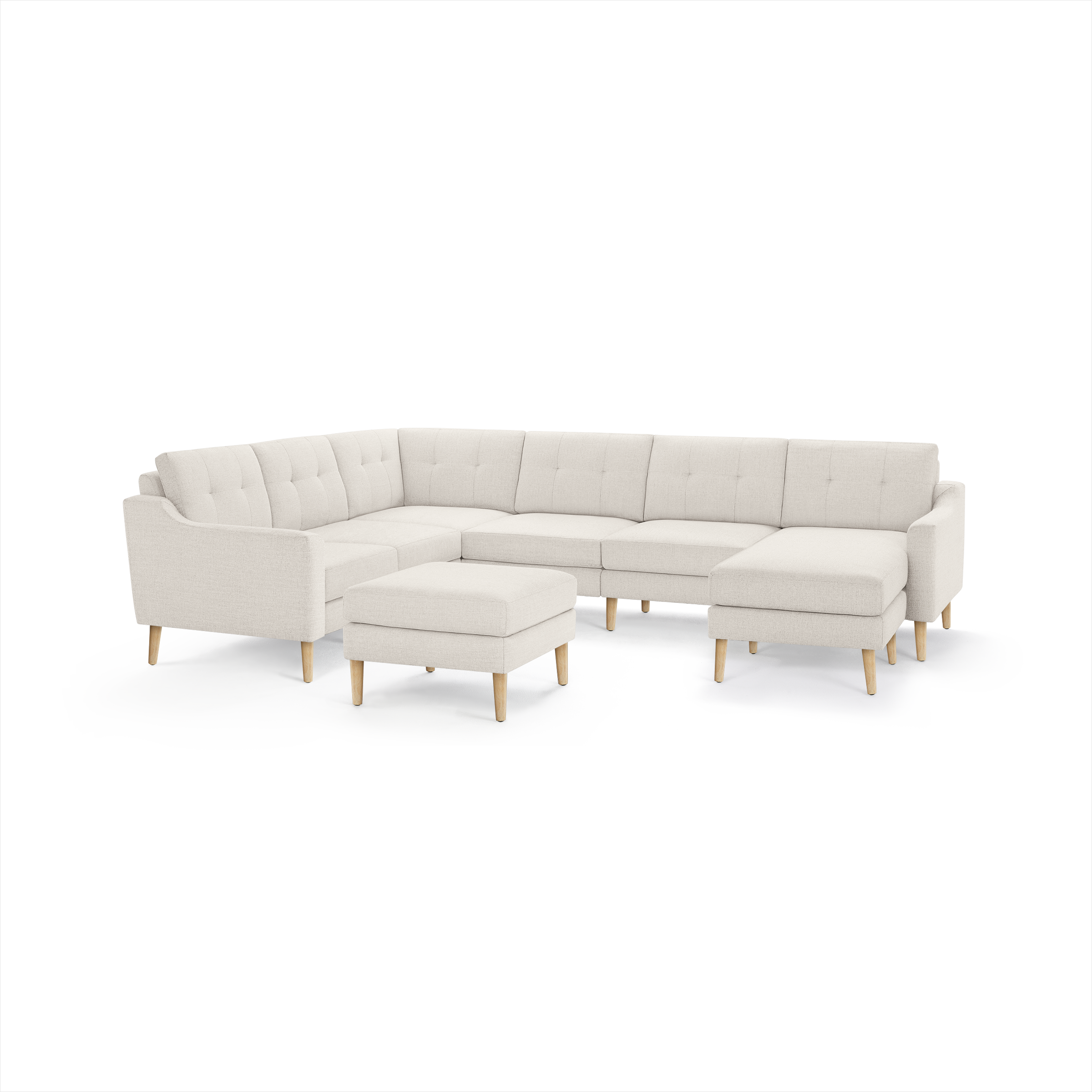 Cream-colored modern sectional sofa with tufted cushions, wooden legs, and a matching ottoman, arranged in an L-shape.
