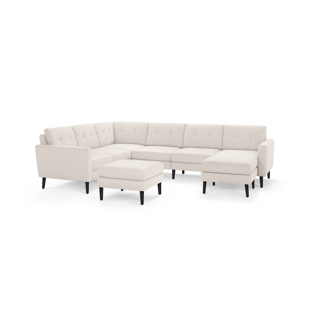 Beige upholstered L-shaped sectional sofa with tufted back cushions, black tapered legs, and matching square ottoman.