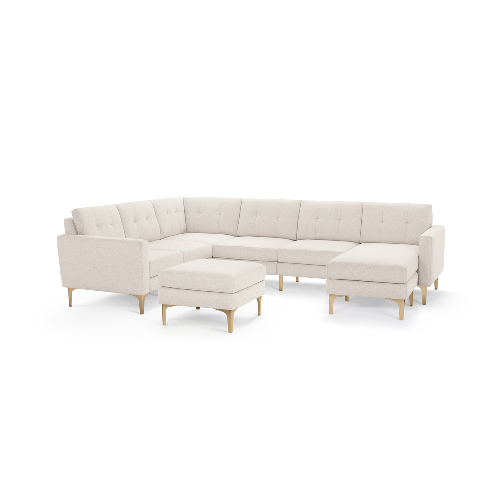 Cream-colored modern sectional sofa with tufted back cushions, wooden legs, and a matching ottoman.