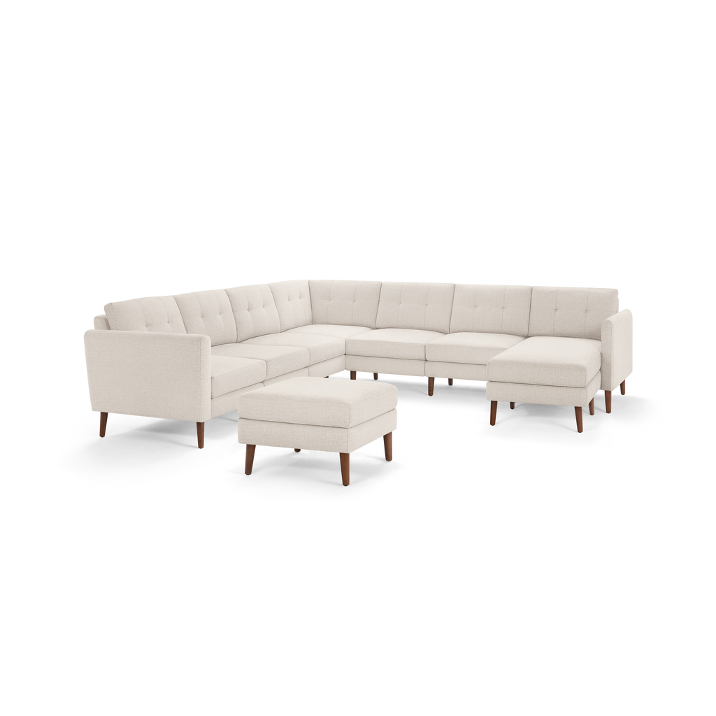 Cream-colored modern L-shaped sectional sofa with tufted back cushions and wooden legs, paired with a matching ottoman.