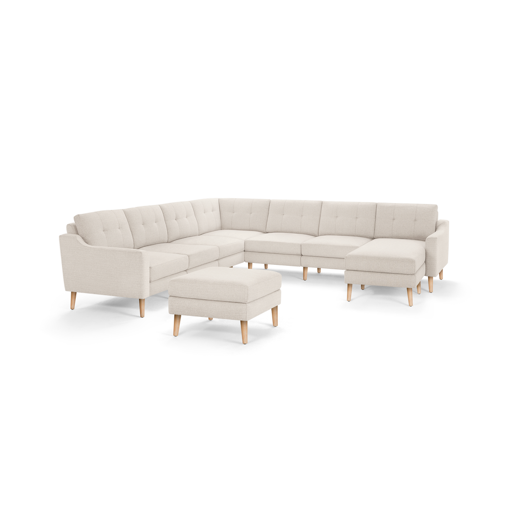 Beige fabric sectional sofa with tufted cushions, wooden legs, and matching ottoman, featuring a modern, minimalist design.