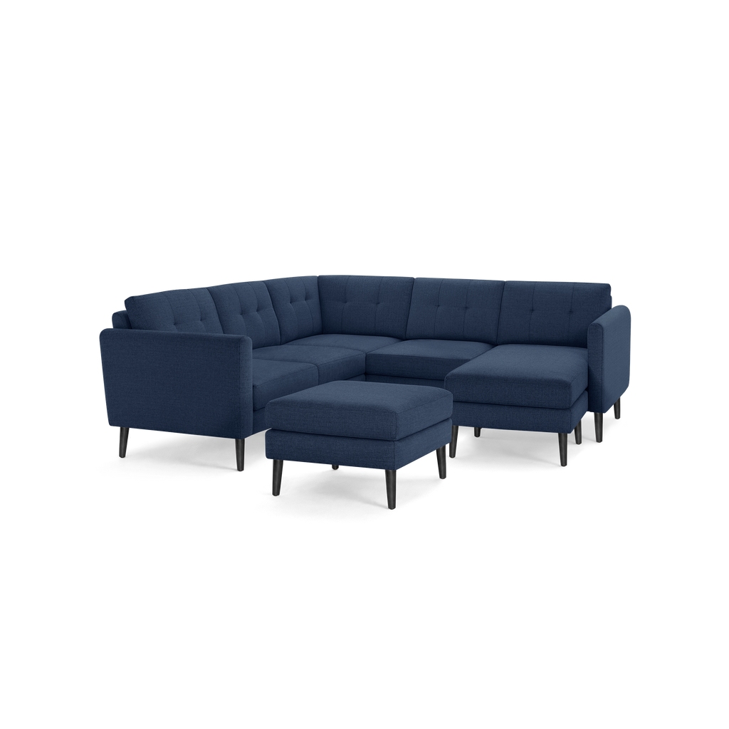 Modern navy blue sectional sofa with tufted cushions and matching ottoman, supported by slender black legs.