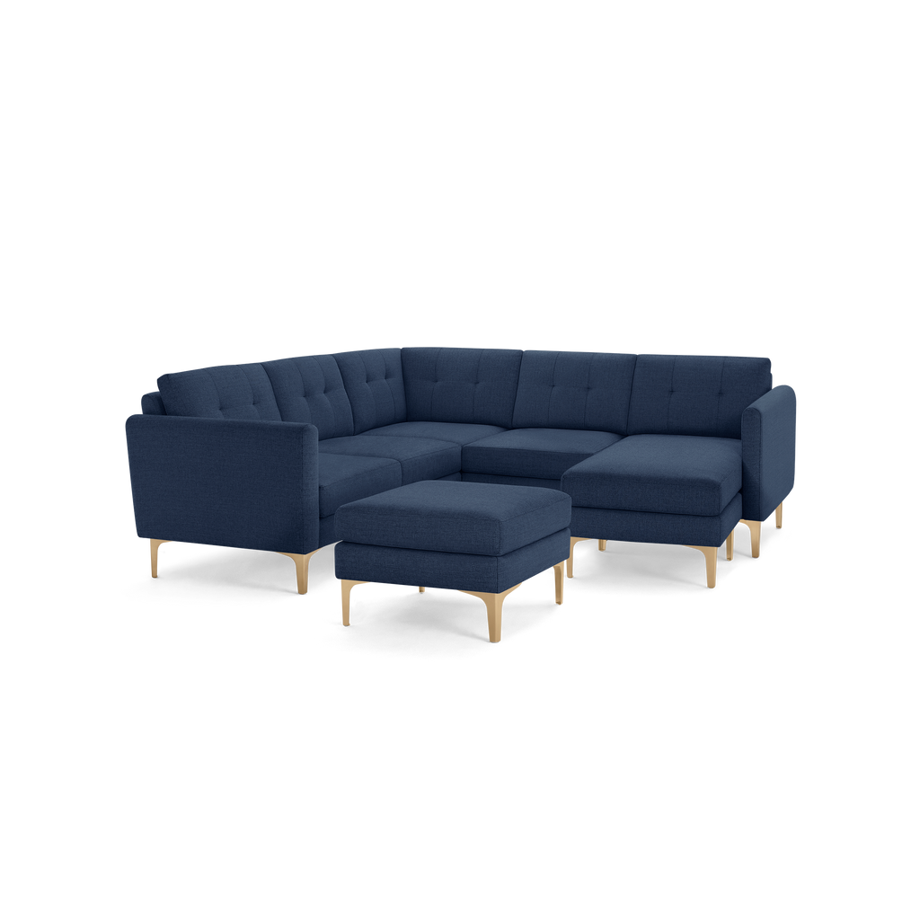Modern navy blue fabric sectional sofa with tufted cushions and light wooden legs, including a matching ottoman.