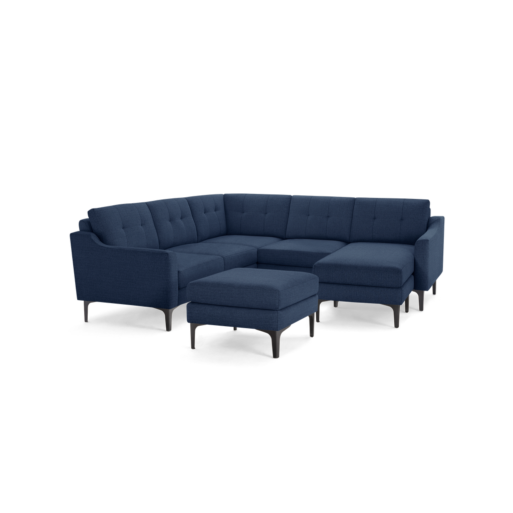 Large modern navy blue fabric sectional sofa with tufted cushions and matching ottoman on black legs.