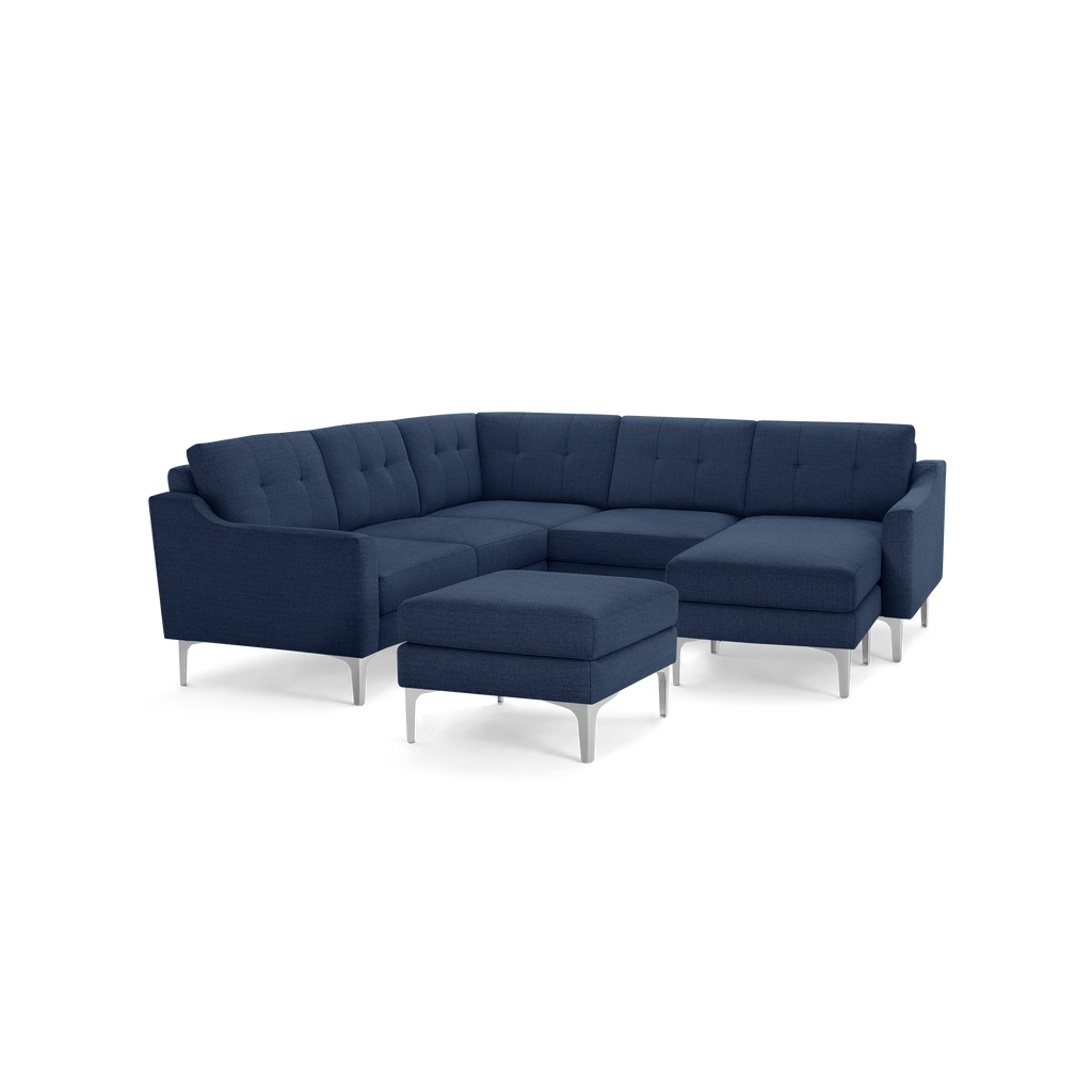 Modern navy blue sectional sofa with tufted back cushions, metal legs, and a matching ottoman on a black background.