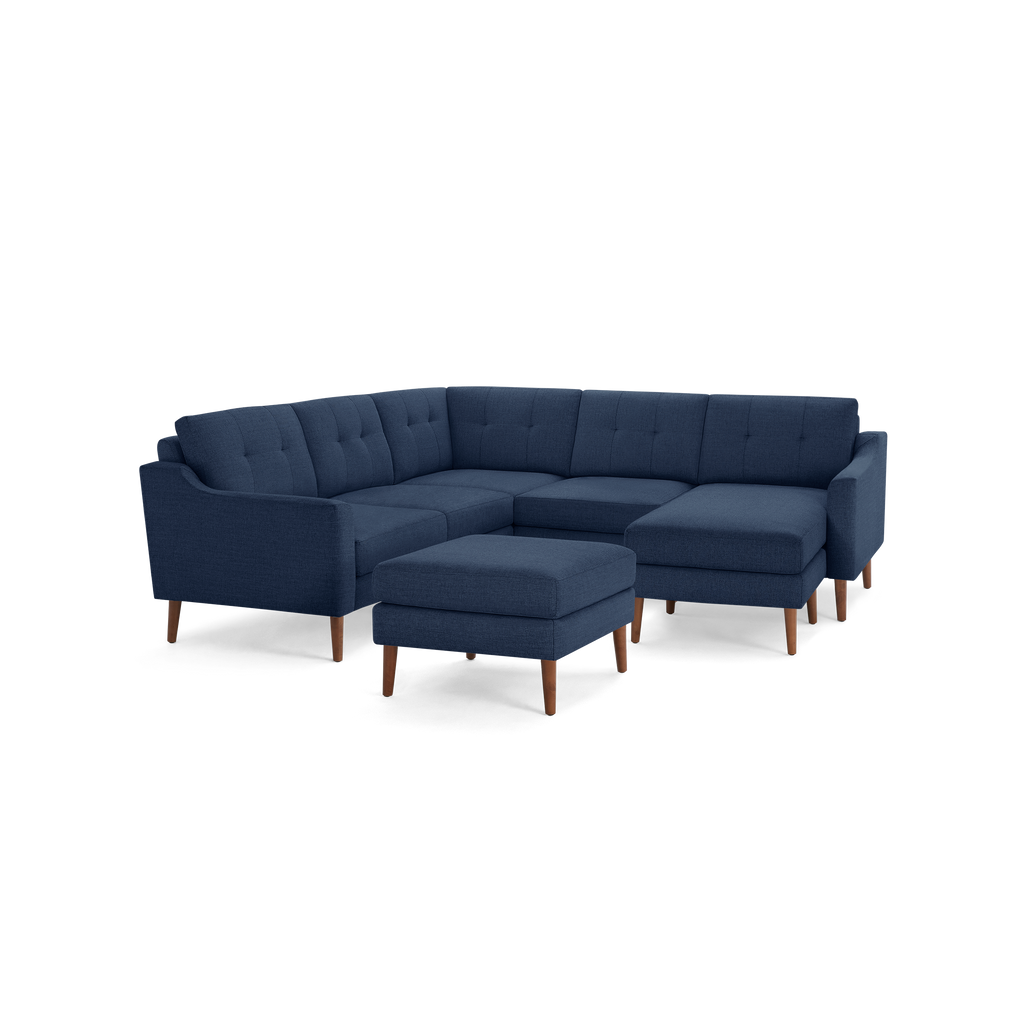 Mid-century modern navy blue fabric sectional sofa with tufted cushions, wooden legs, and a matching ottoman.