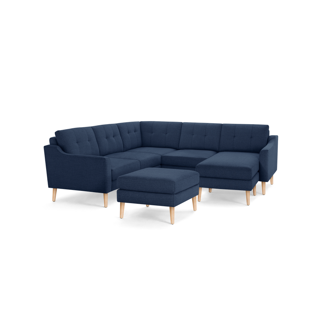 Modern navy blue fabric sectional sofa with tufted cushions, wooden legs, and matching ottoman, ideal for spacious living rooms.