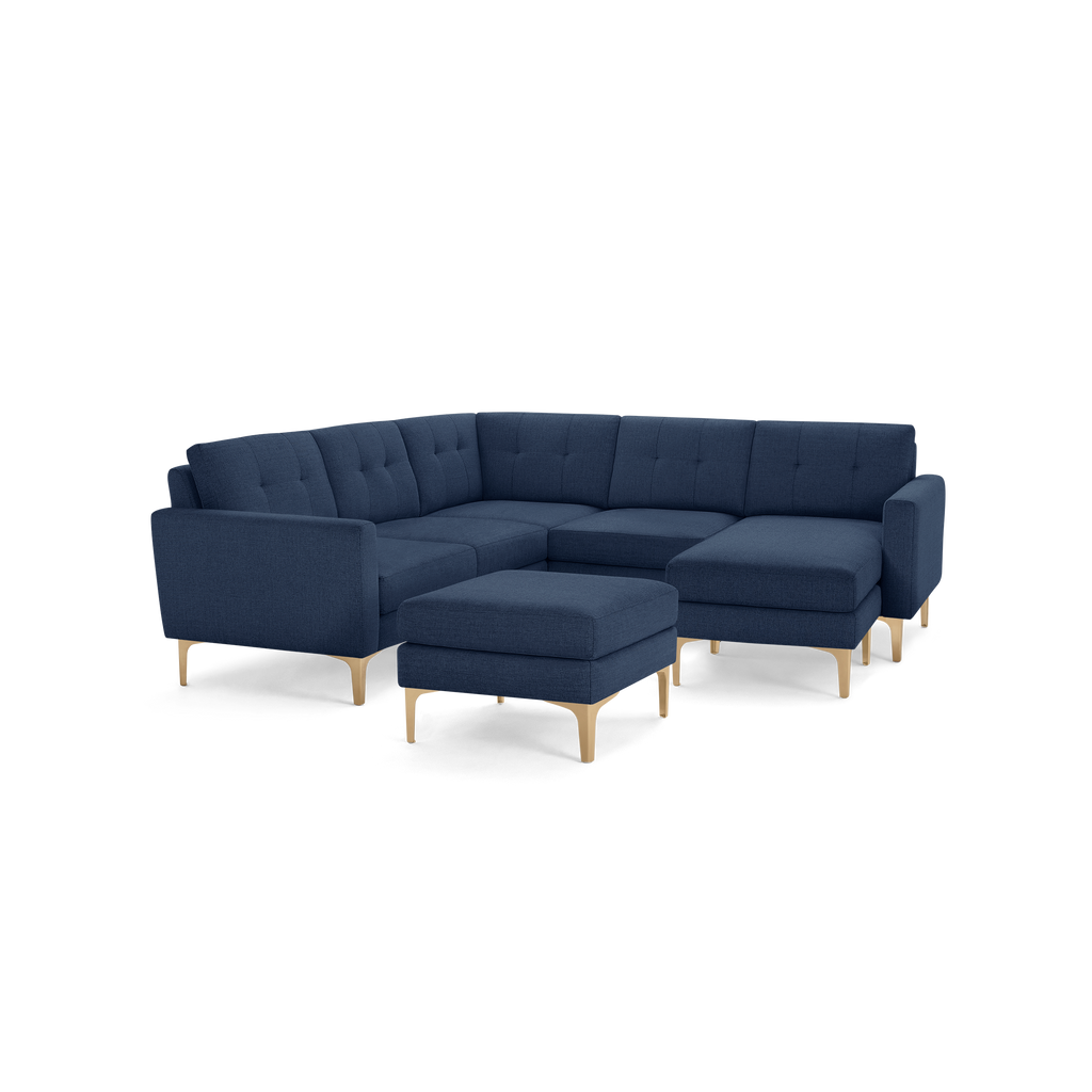 Modern navy blue fabric sectional sofa with tufted cushions, wooden legs, and a matching ottoman.