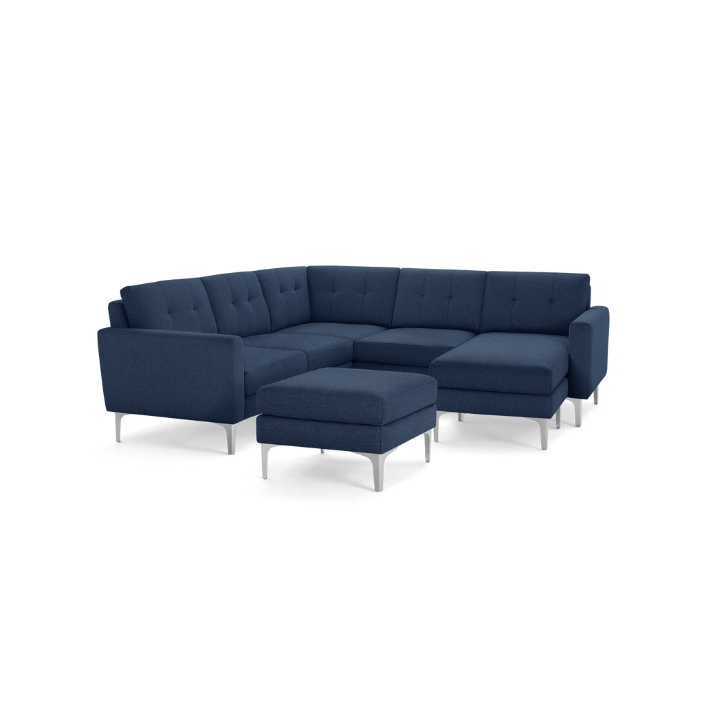 Navy blue fabric sectional sofa with tufted cushions, metal legs, and a matching ottoman on a black background.