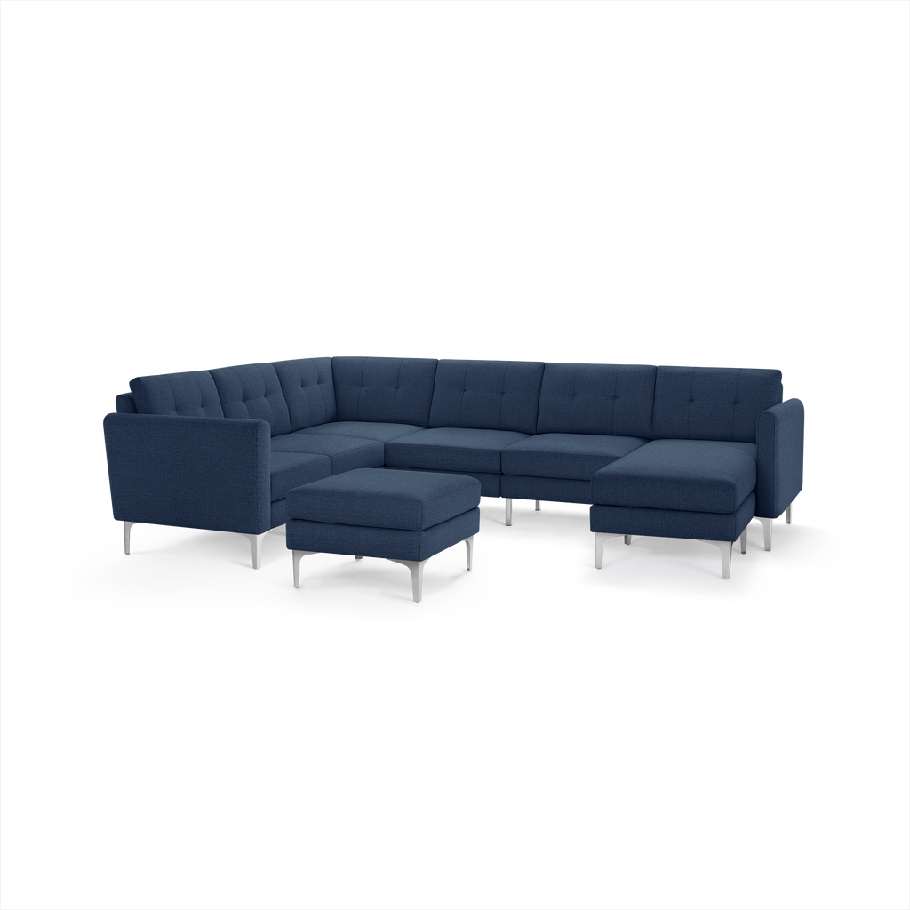 Modern navy blue sectional sofa with tufted cushions, metal legs, and a matching ottoman, designed for spacious comfort.