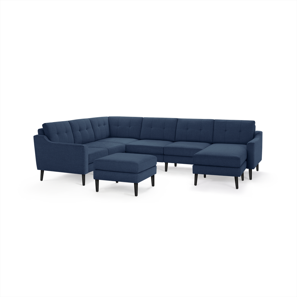Modern navy blue sectional sofa with tufted cushions, black tapered legs, and matching ottoman on white background.