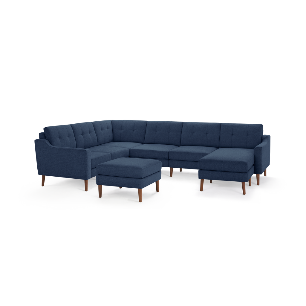 Modern navy blue fabric sectional sofa with tufted cushions, wooden legs, and matching ottoman, designed for spacious seating.