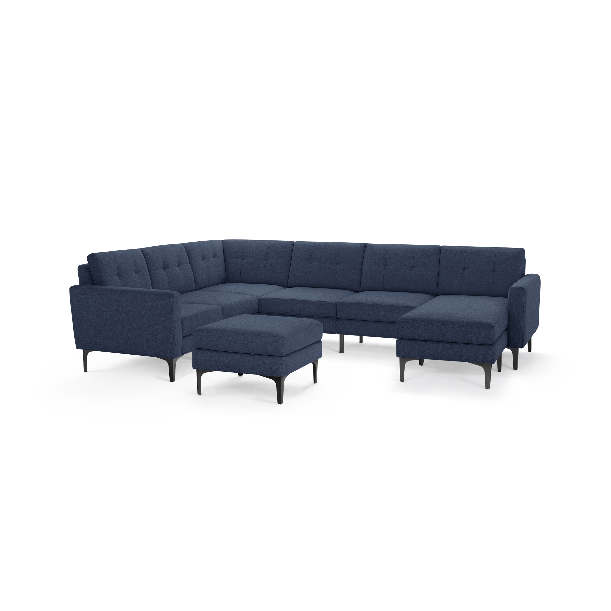 Modern L-shaped sectional sofa in dark blue fabric with tufted cushions and matching ottoman, supported by black legs.