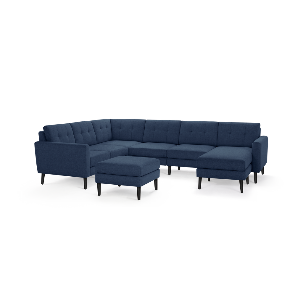 Modern deep blue fabric sectional sofa with tufted cushions, black tapered legs, and matching square ottoman.