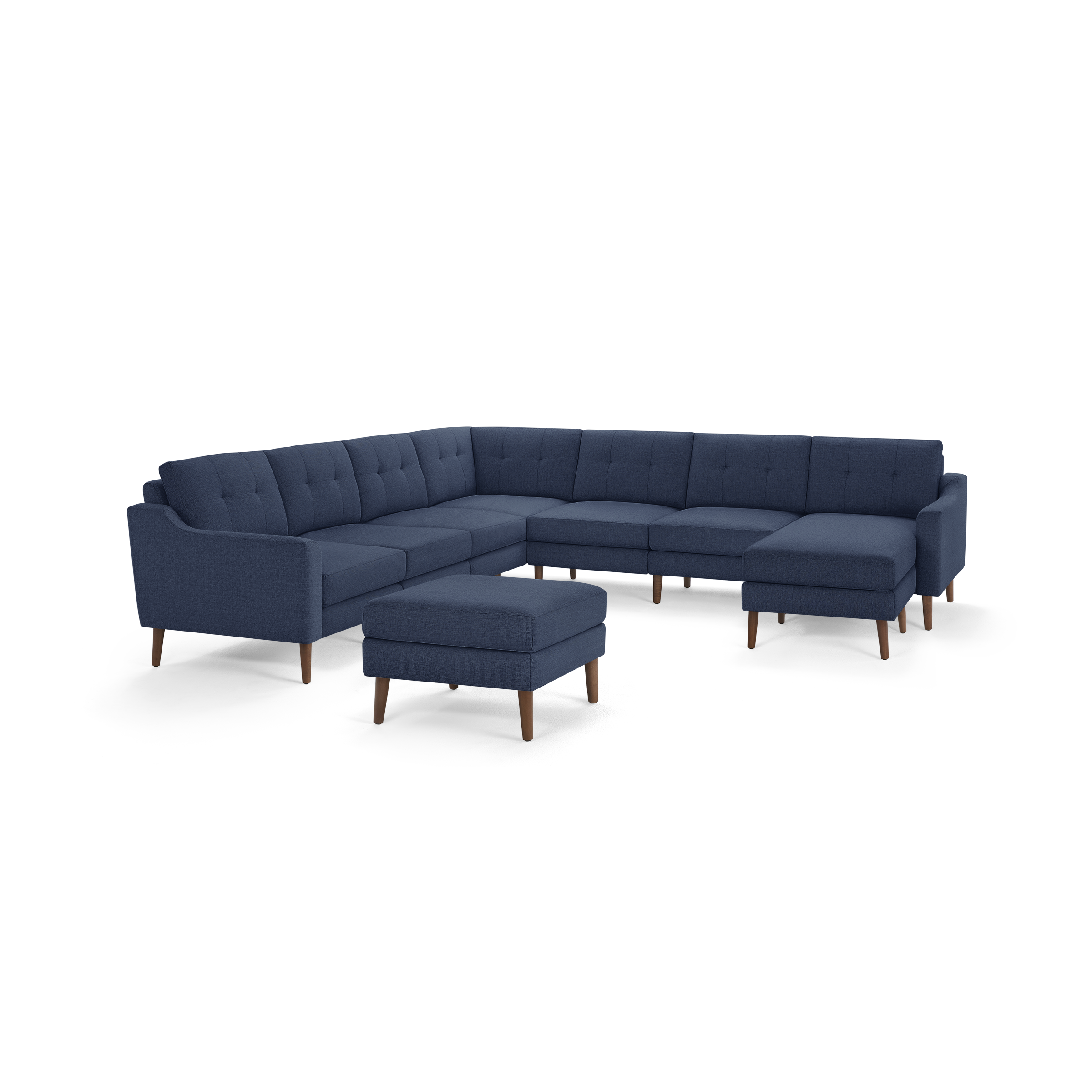 Large navy blue L-shaped sectional sofa with tufted back cushions, matching ottoman, and wooden legs.