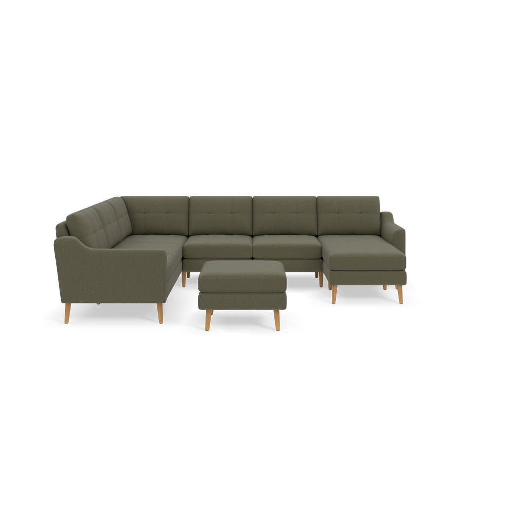 Moss green fabric sectional sofa with tufted back cushions and matching ottoman on wooden legs against black background.