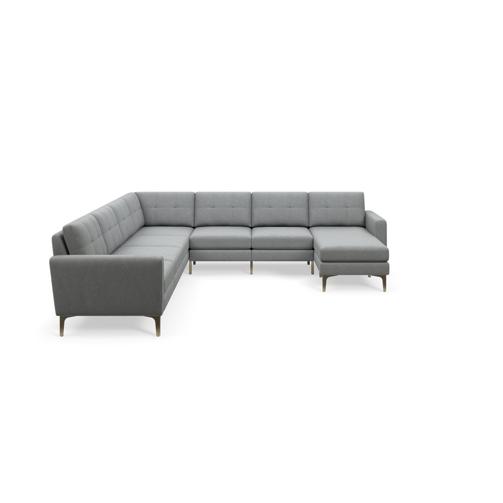 Modern gray L-shaped sectional sofa with tufted back cushions and slim gold legs, isolated on black background.