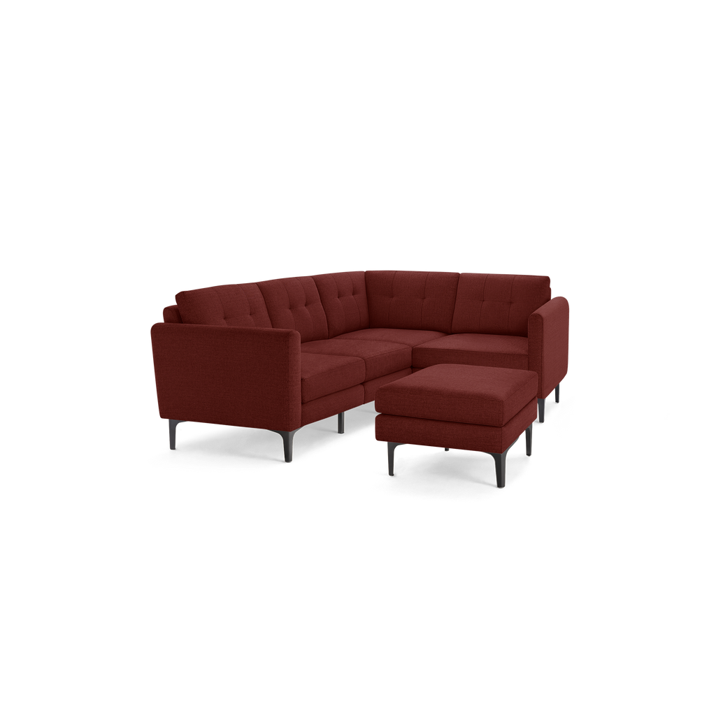 Modern L-shaped sectional sofa in deep red fabric with tufted backrests and matching ottoman on black metal legs.
