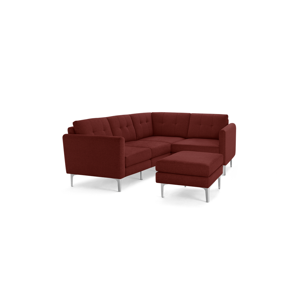 Modern L-shaped sectional sofa in deep red fabric with tufted cushions and silver metal legs, including a matching ottoman.