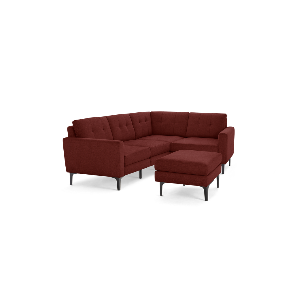 Maroon fabric upholstered L-shaped sectional sofa with tufted cushions and matching ottoman on black angled legs.